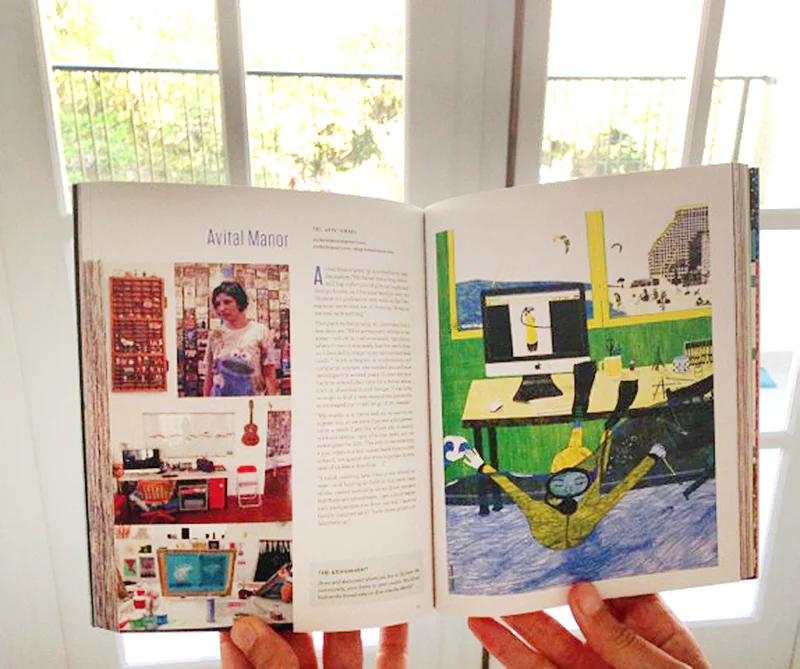 Avital holds her book in front of the window she drew as part of her Work/Life 3 illustrations.