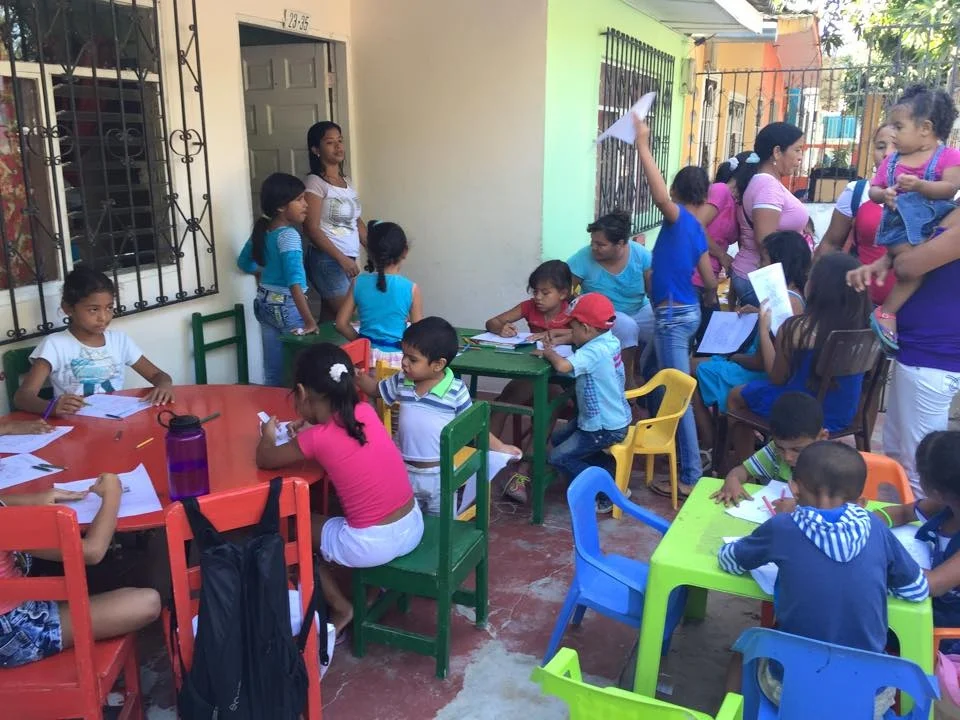 Children gather at the front of the house to learn about God's love for them.