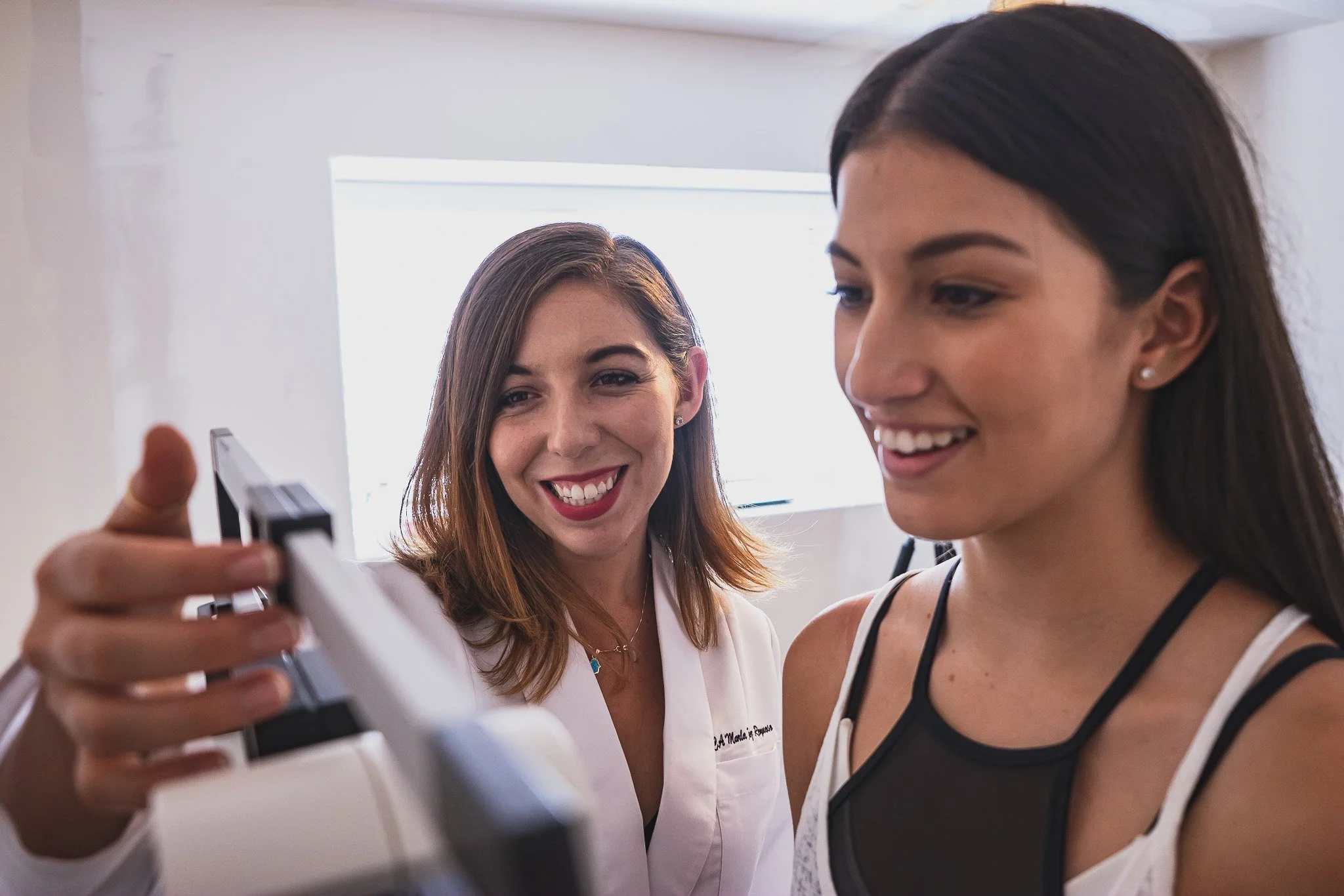 A medical professional showing a woman a set of dental X-rays in a bright room.