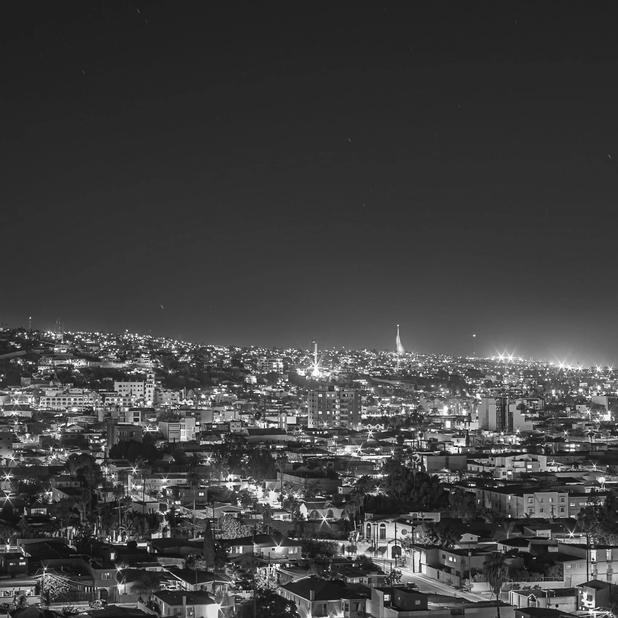 Nighttime cityscape of a densely populated urban area with illuminated buildings and streets, under a dark sky