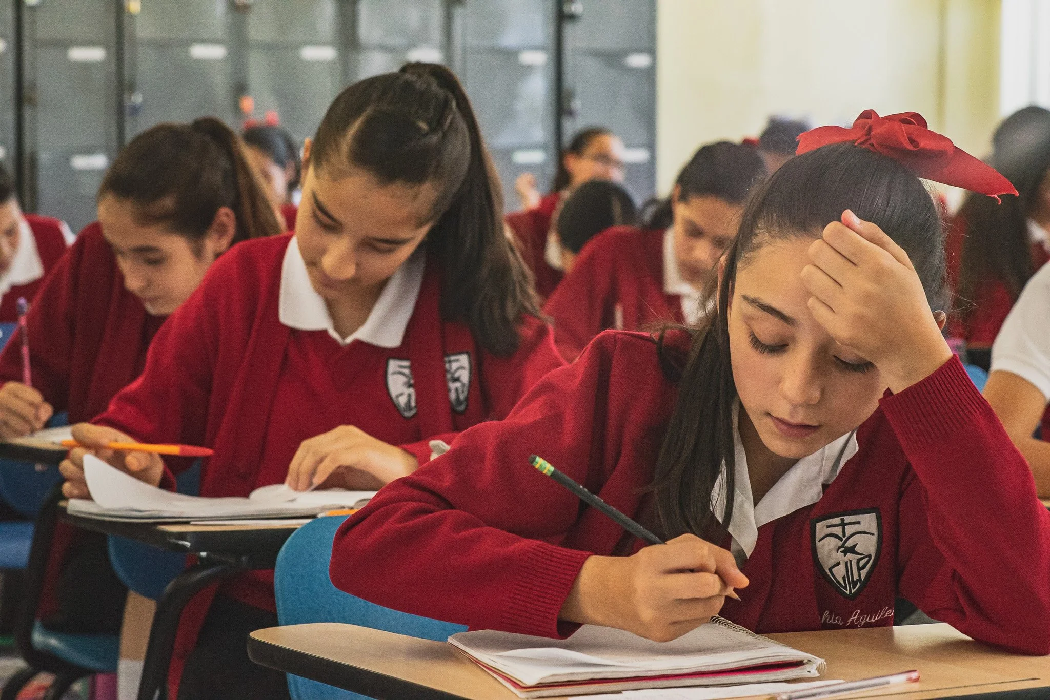 Students in red uniforms studying and taking notes in a classroom.