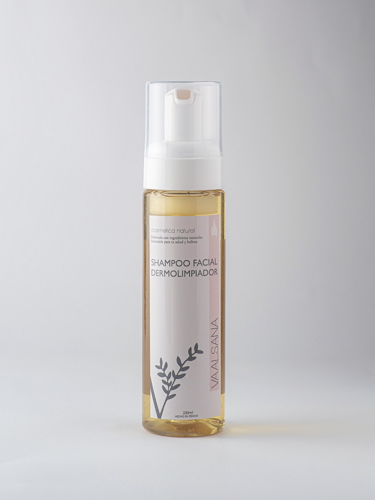 A clear plastic pump bottle with a light yellow liquid soap labeled 'Shampoo Facial Dermolimpiador' and 'Vainilla SANA' against a plain light background.