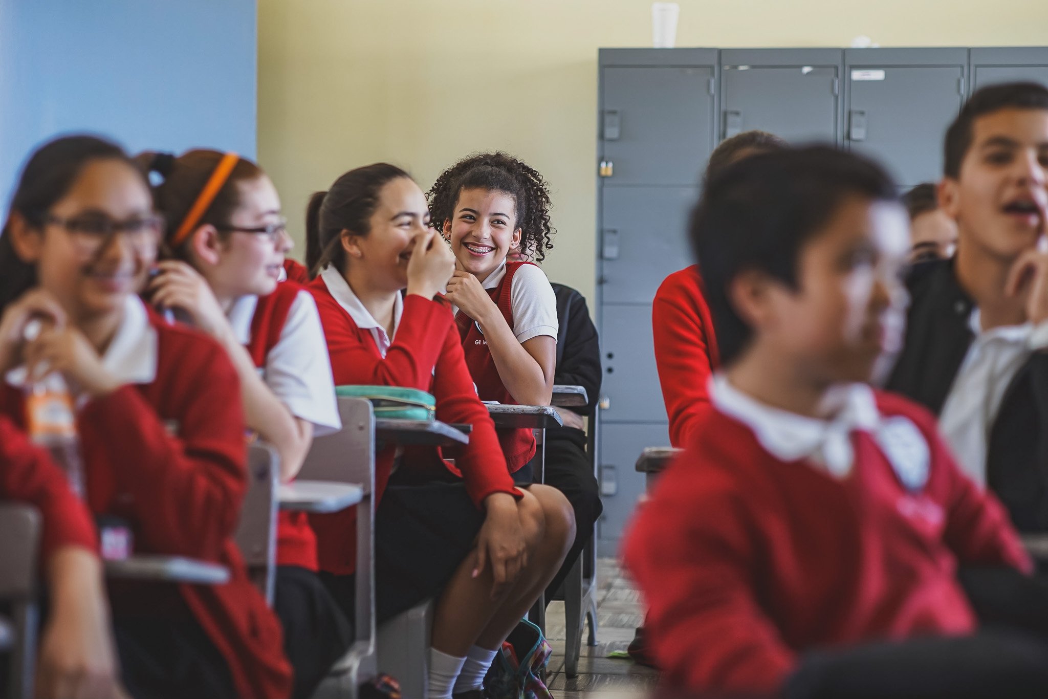 Classroom of students in red and white uniforms laughing and smiling