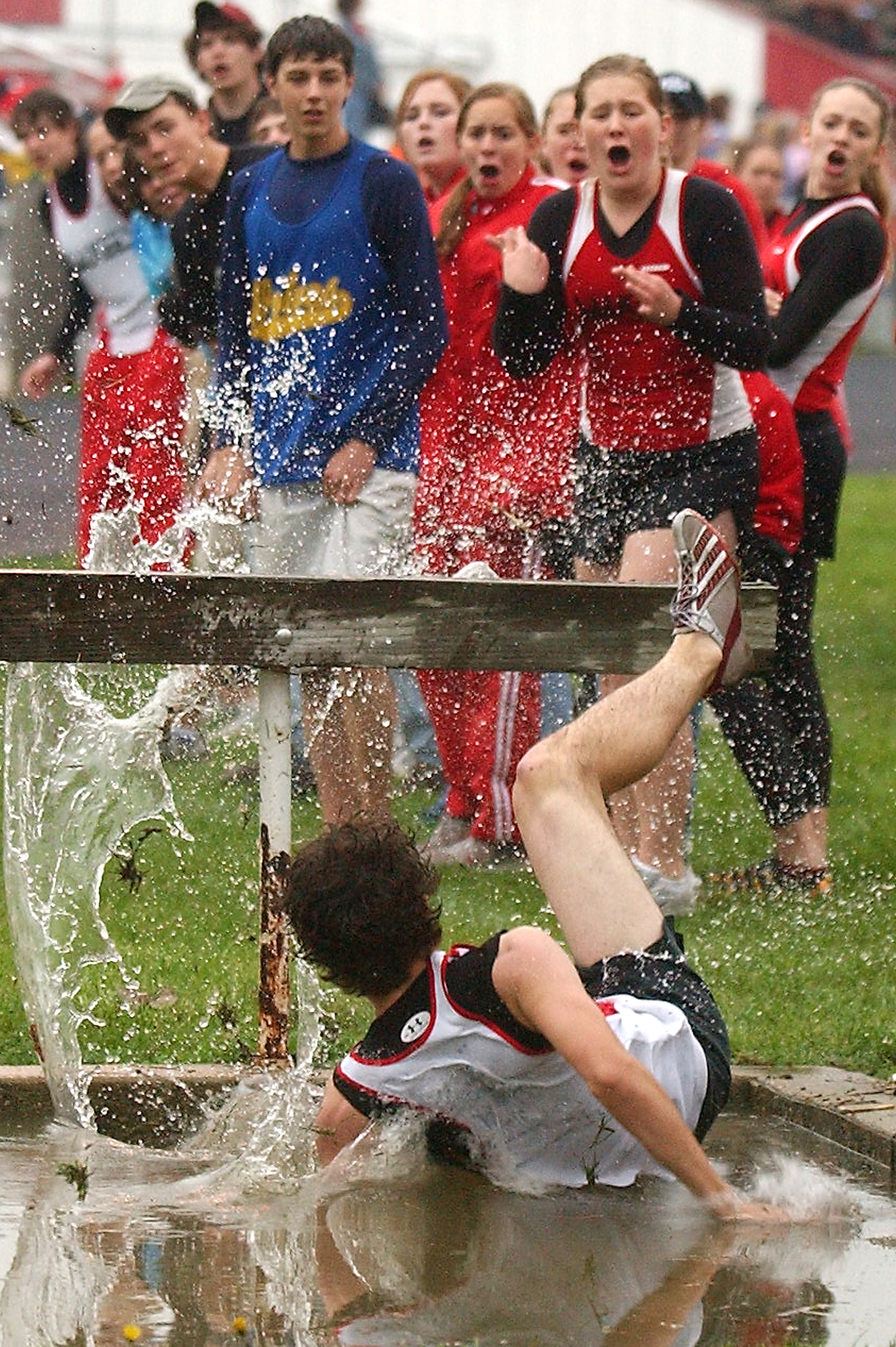  Pittsfield High School students react to their teammate Justin Critchelow's backward fall into the water after catching his foot during the boys steeplechase at the Saukee Olympics track meet.  Despite the fall, Critchelow maintained his lead and wo