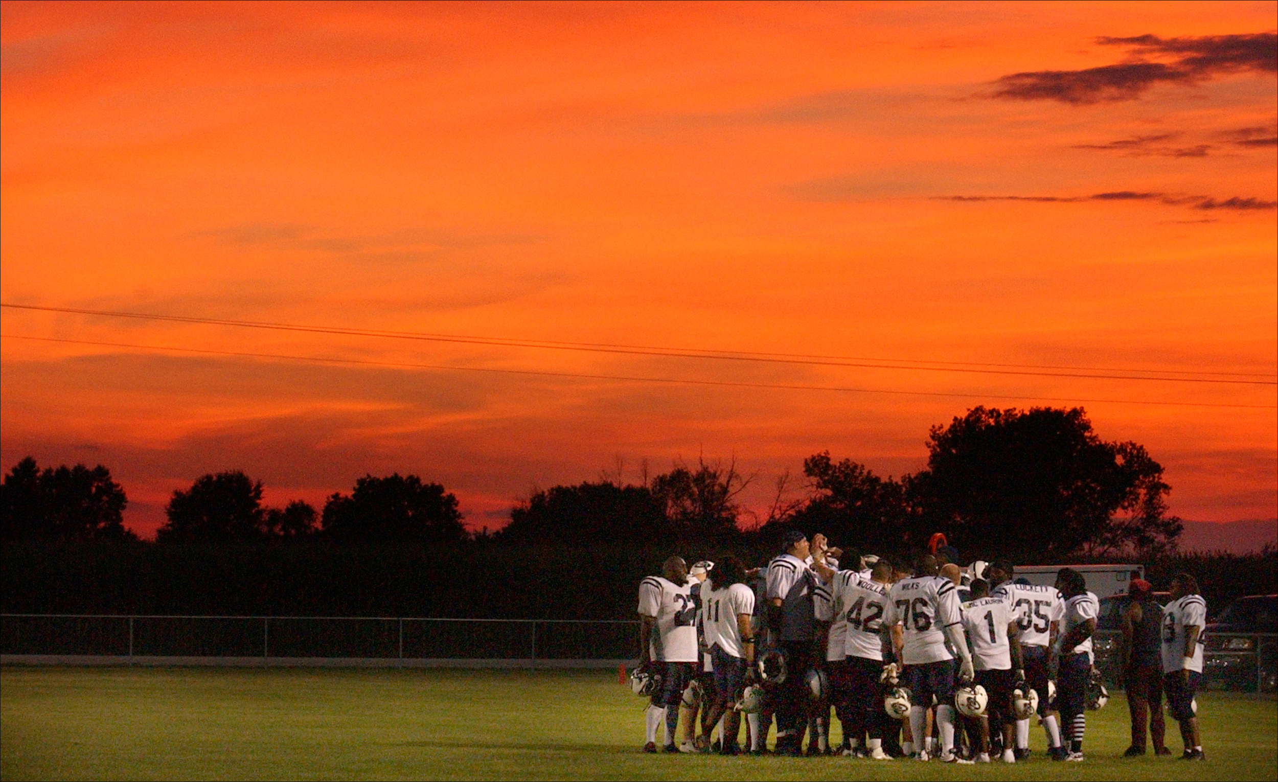 Members of the Northeast Missouri Cyclones briefly went over their strategy for the second half of their game at the Van-Far High School football field in Vandalia, Mo. where temperatures eased down under an orange, summer sky. The minor league football team now plays all of their home games on the Van-Far High School field after sponsors in St. Louis sold the team..