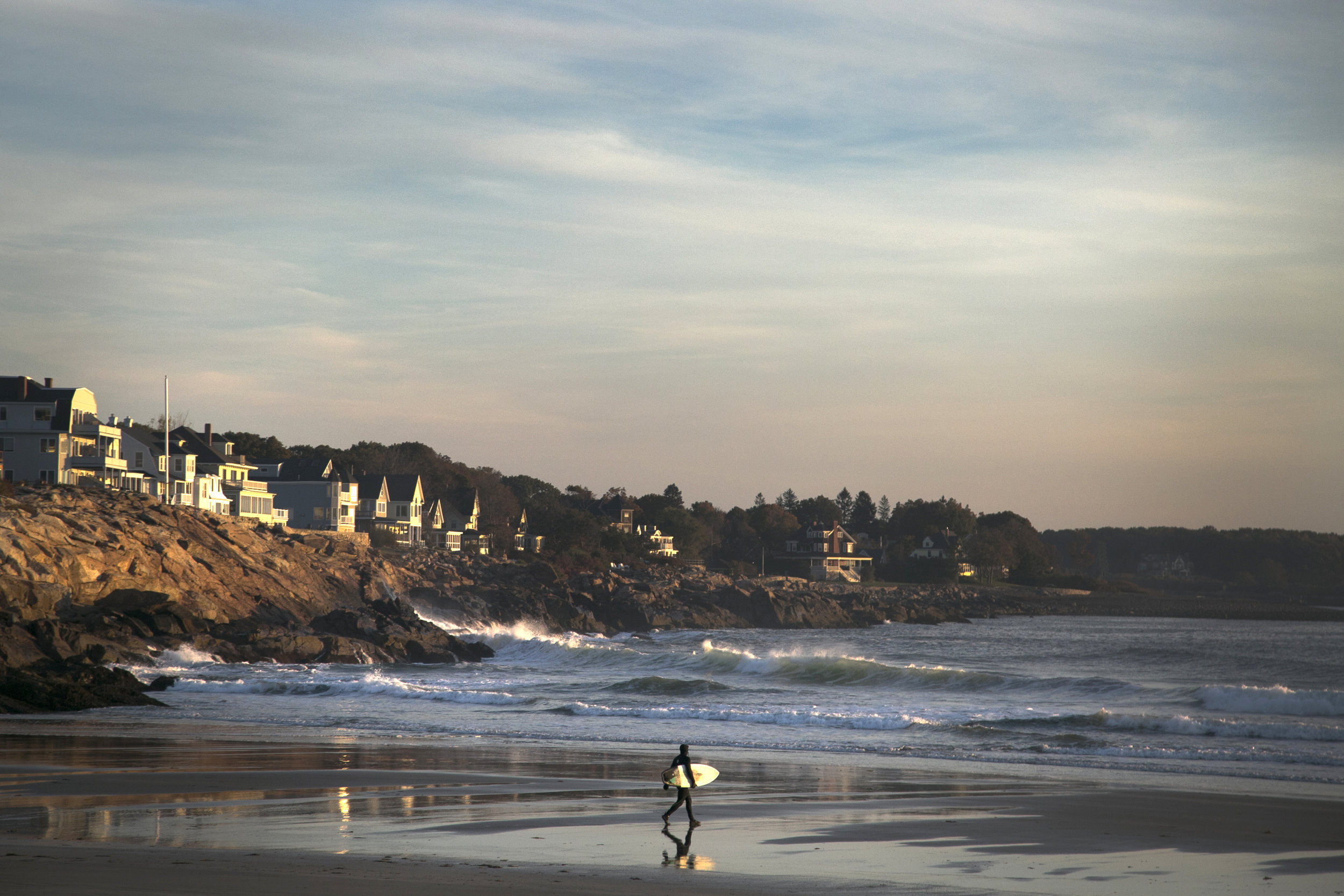  A surfer enters the waters off the coast of York, Maine where wave chasers flock to beaches in mid-October in search of good surfing days.  