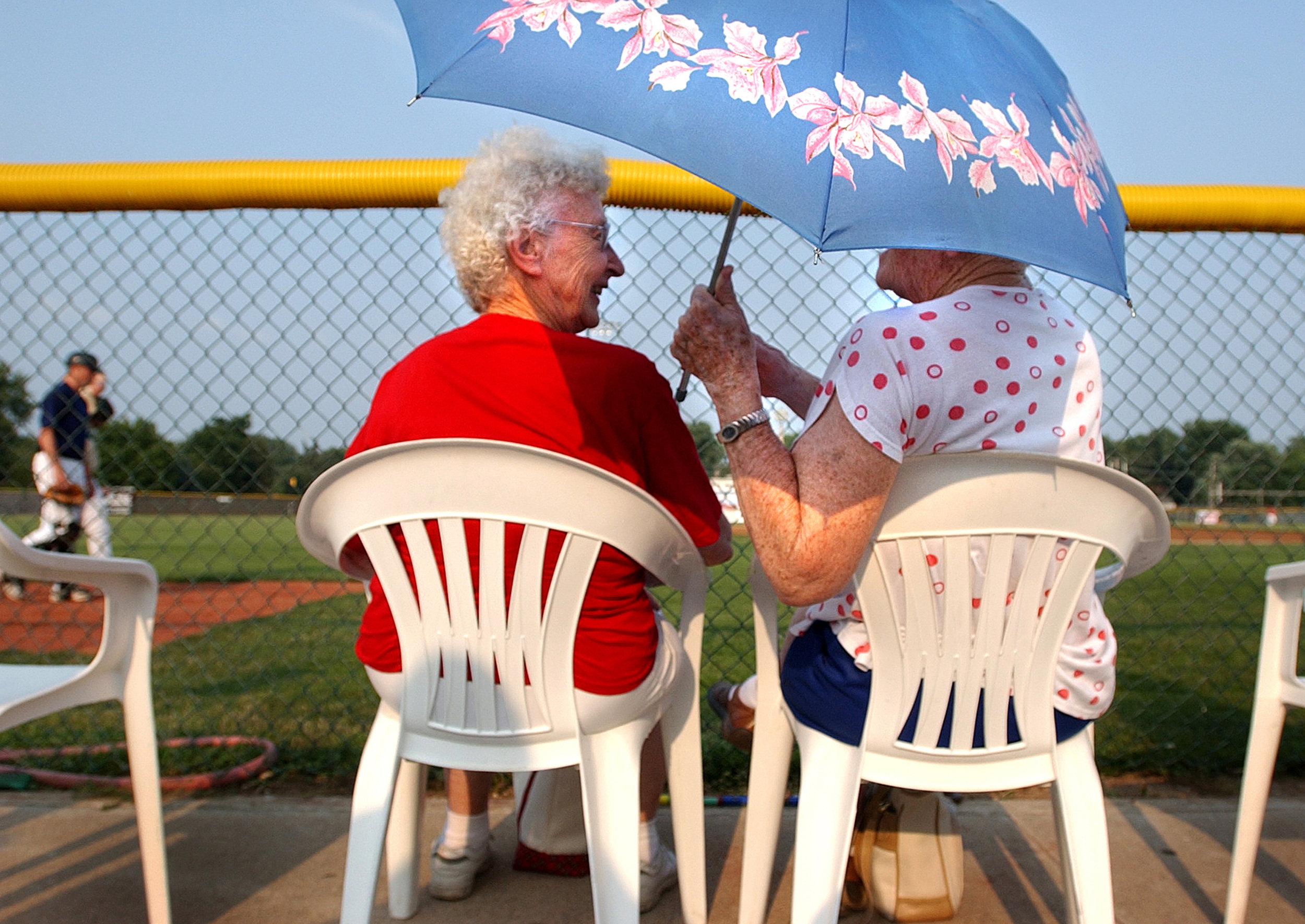  Recently widowed, Letha Althoff, left, and Florence Lummer decided not to stop going to the Quincy Gems games just because their husbands had died. The two never miss a game and always take turns holding the umbrella to block the summer sun. 