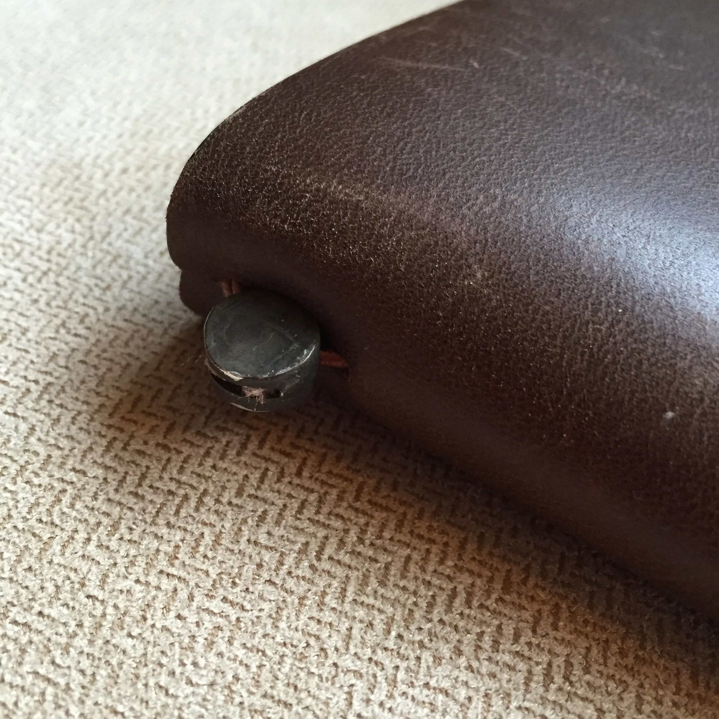 The tin clasp lies at the top of the spine. It fastens the elastic band that holds the refills inside the notebook as well as securing the bookmark.