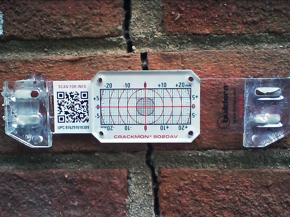 FIGURE 5. Buildera CRACKMON 5020AV crack monitor installed at position No. 3 on South wall utility room (slab on grade). Initial crack width varies between 0.120 and 0.140 inches (3.05 to 3.56 mm). Inside caliper measurement reference: 4.583 inches.