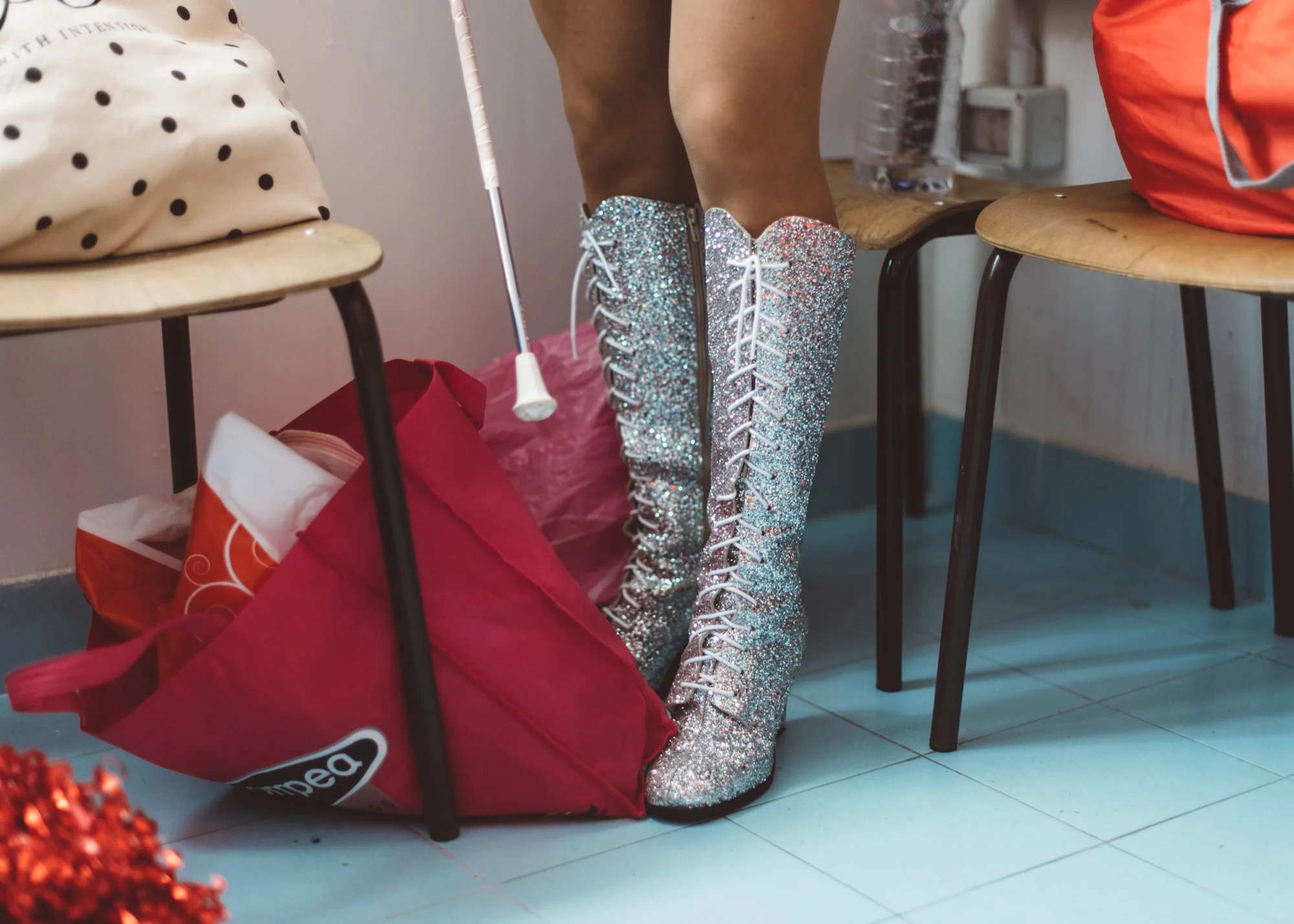 Martina Franca, 2018. A majorette wearing sparkling boots gets changed in the locker rooms of a school gymnasium.