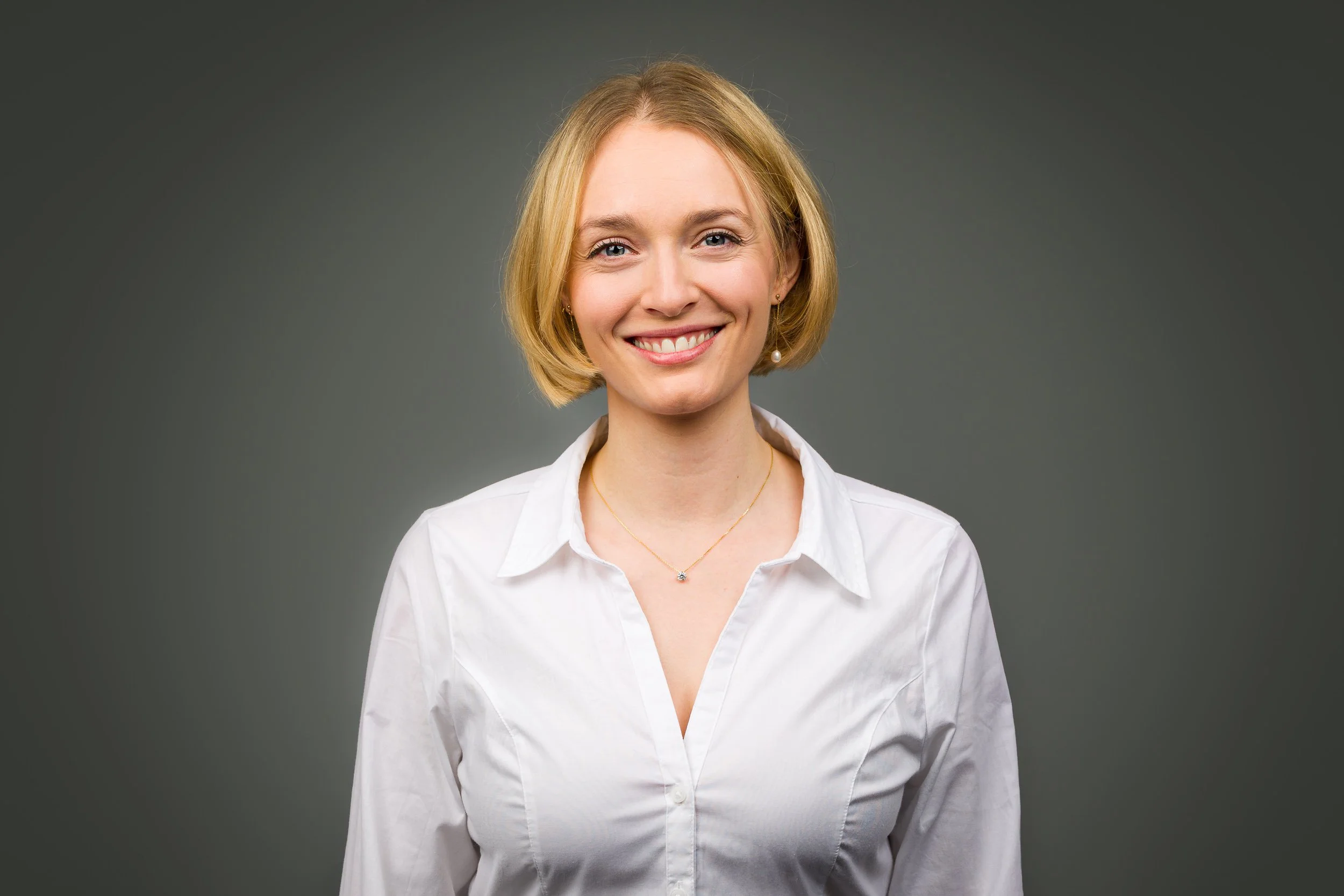 Headshot of a smiling woman against a grey background