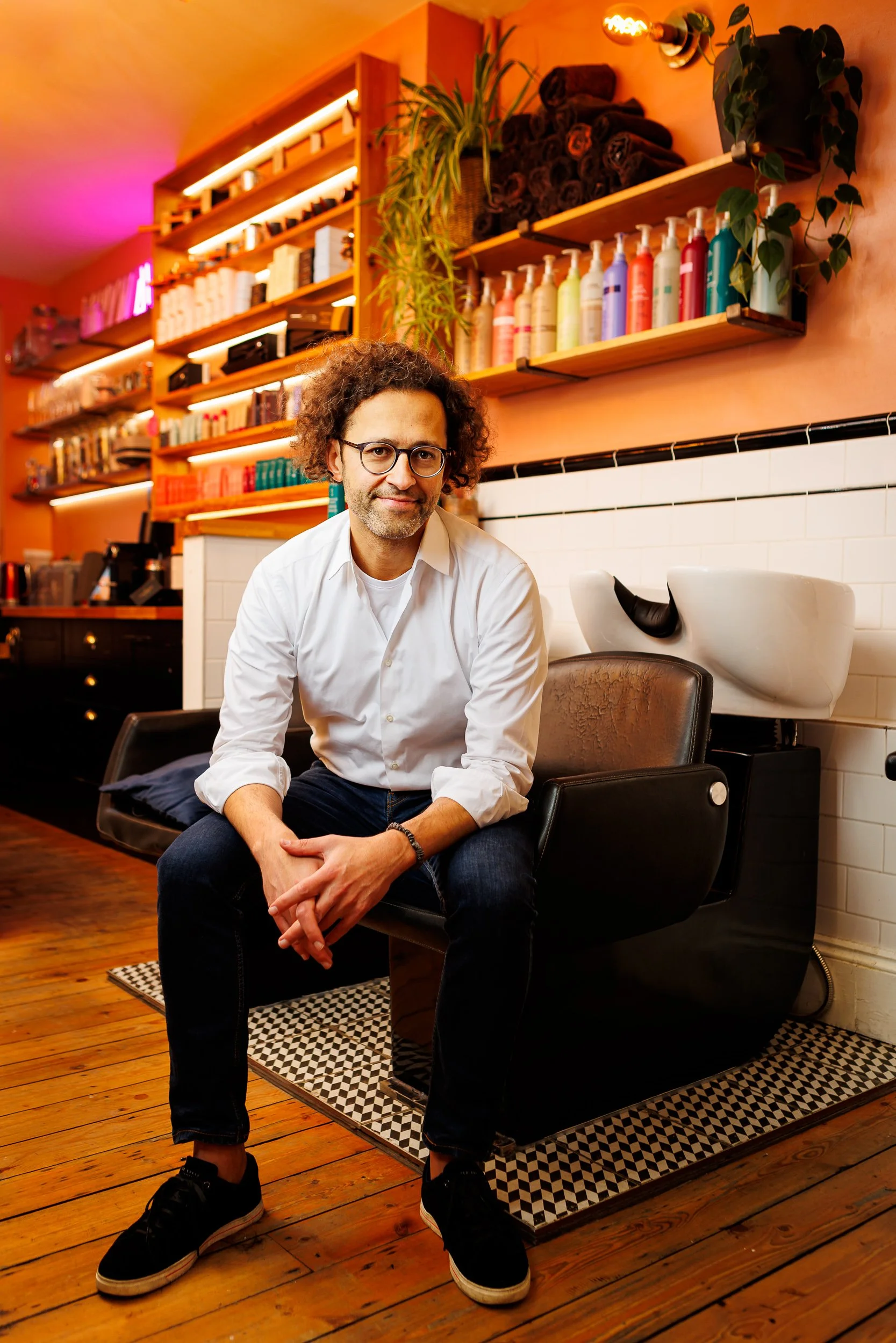 A hairdresser poses for a portrait in his salon in Soho, London