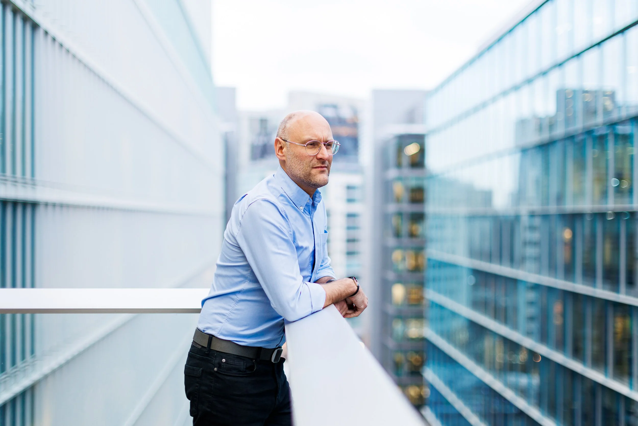 A businessman looks out from a high balcony across London