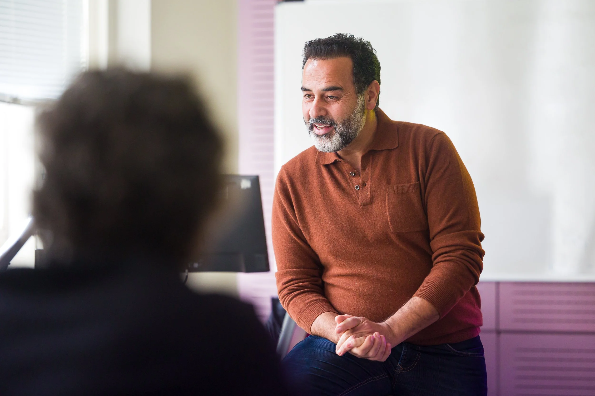 University lecturer sitting on a desk