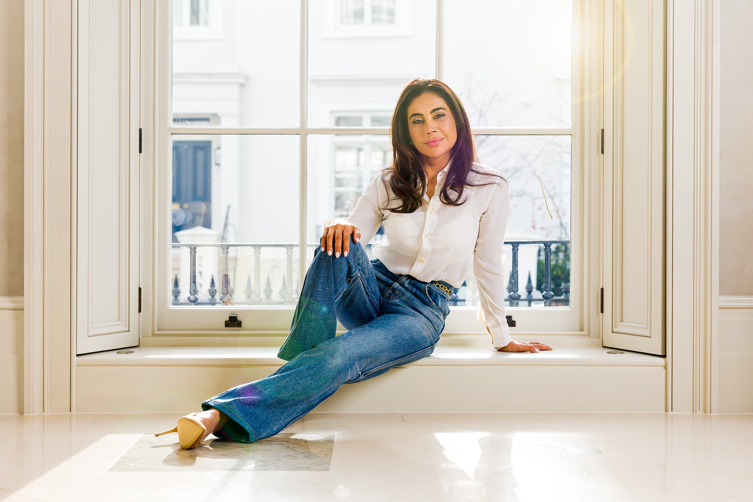 Woman sits at the base of a large window