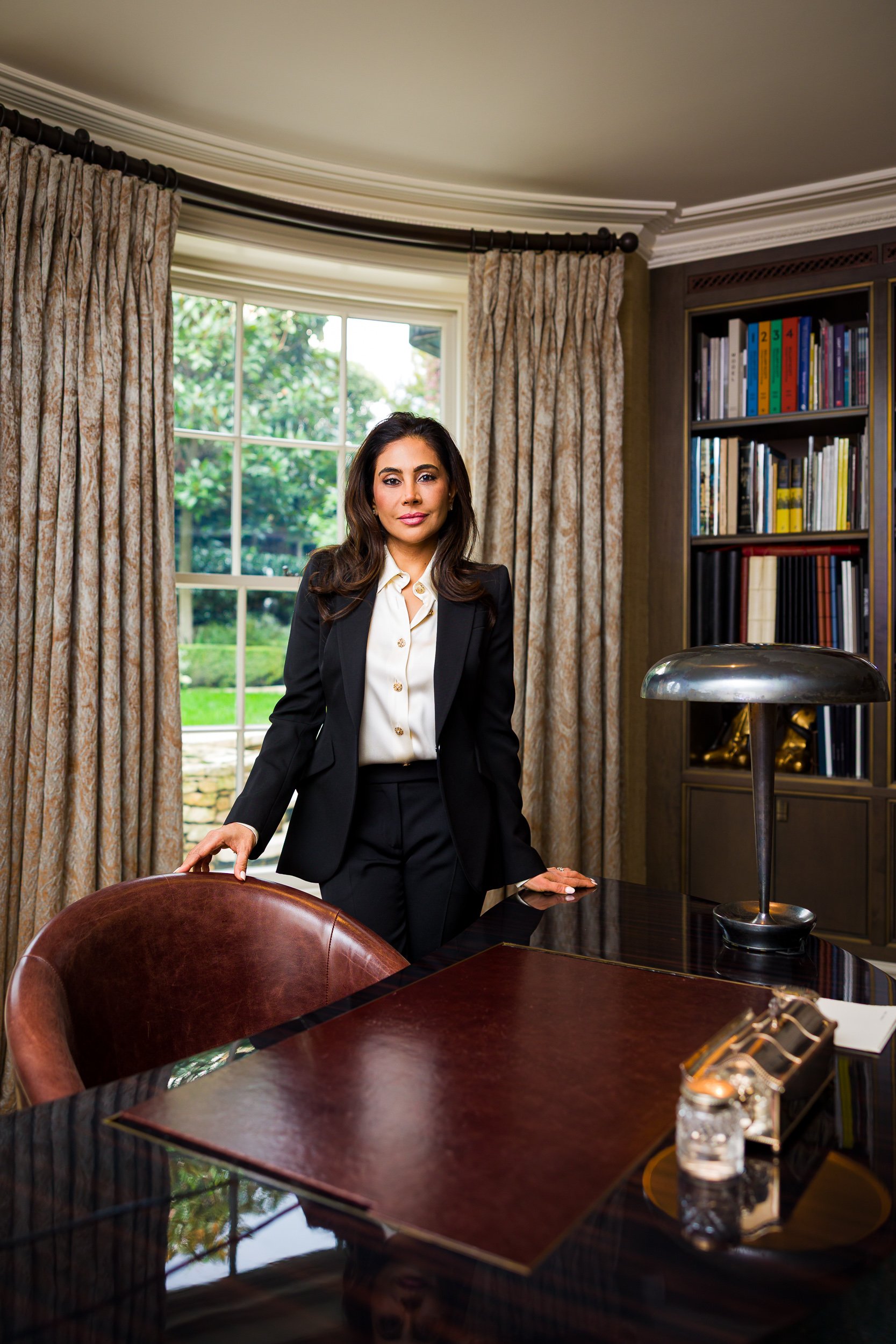 A businesswoman in a suit stands behind her desk
