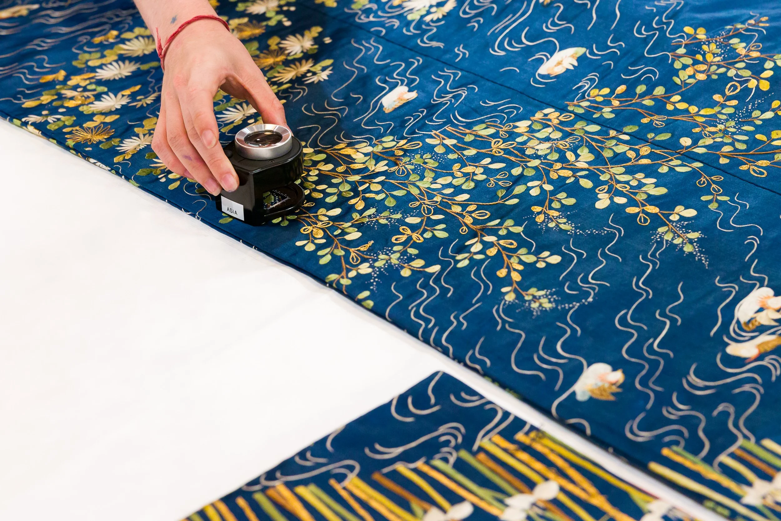 A hand holds a magnifying glass over a Kimono