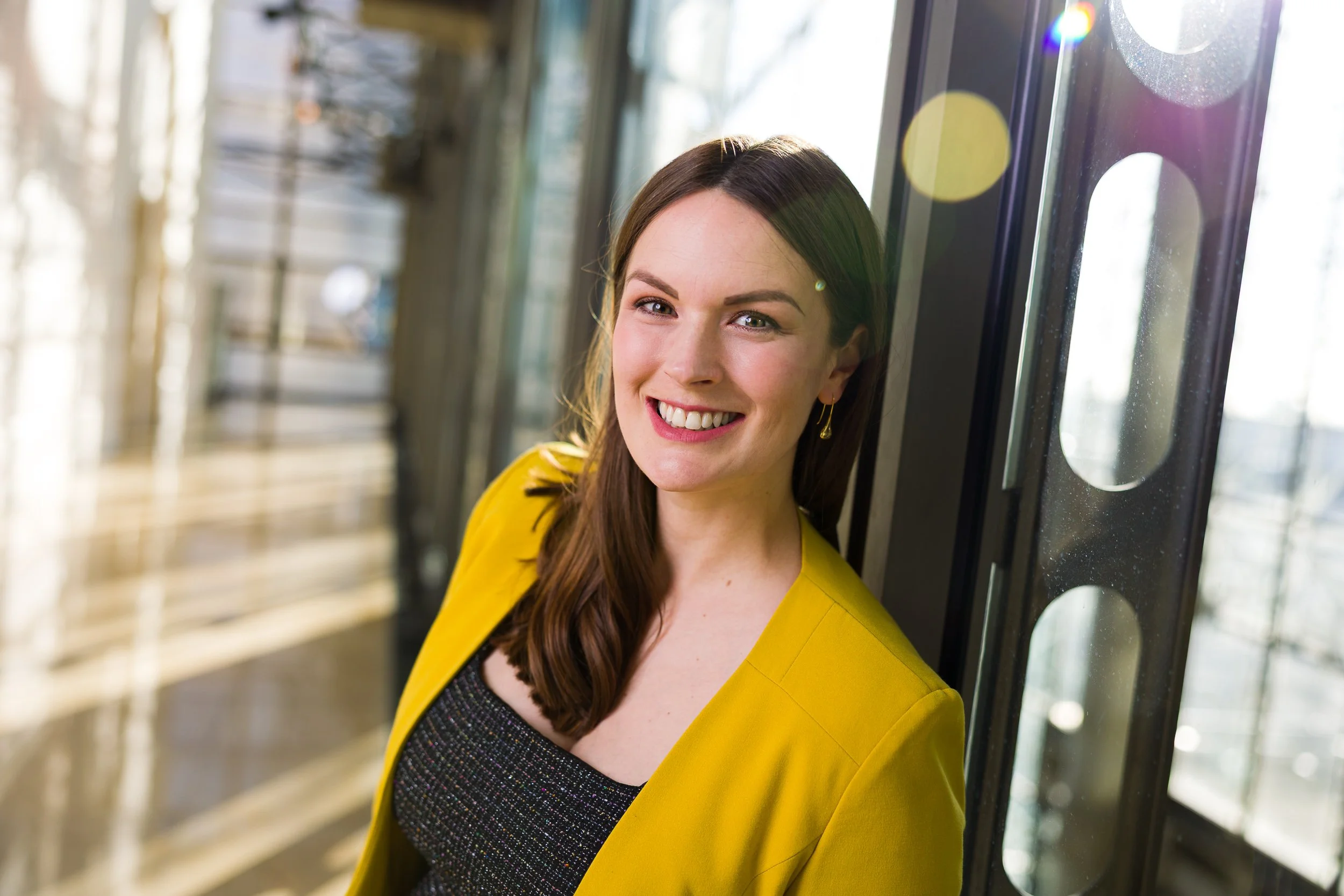 Backlit headshot of a smiling woman in an office