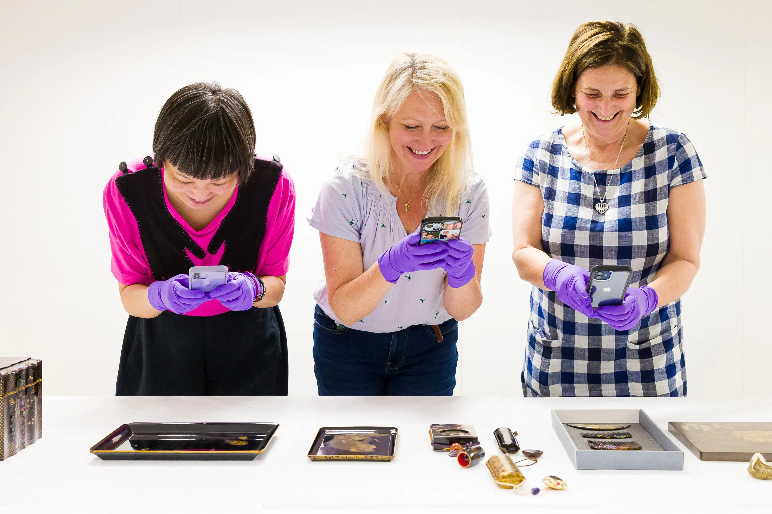 Three students photographing lacquerware at the V&A museum