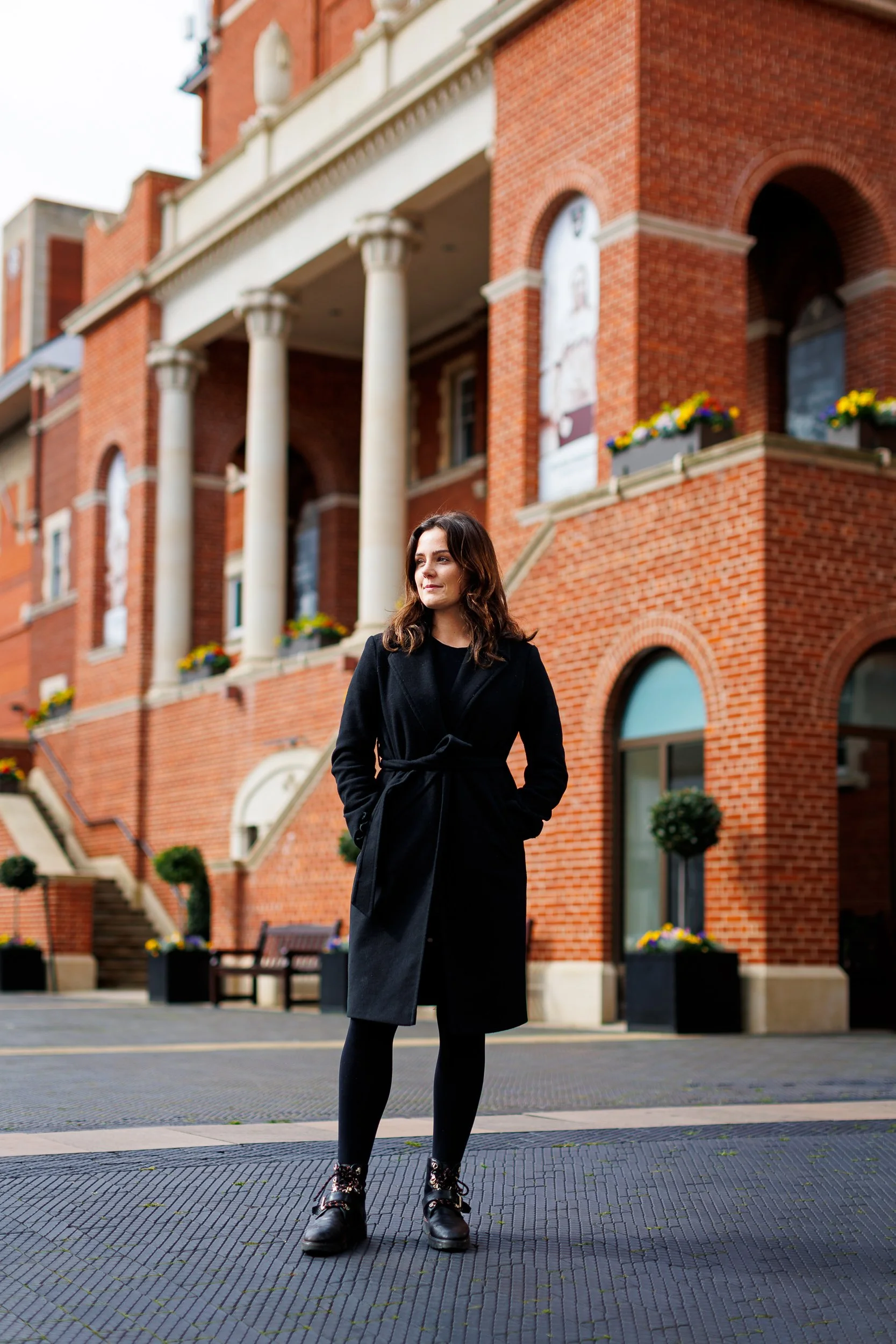 A woman stands in front of the main entrance to the Oval cricket ground