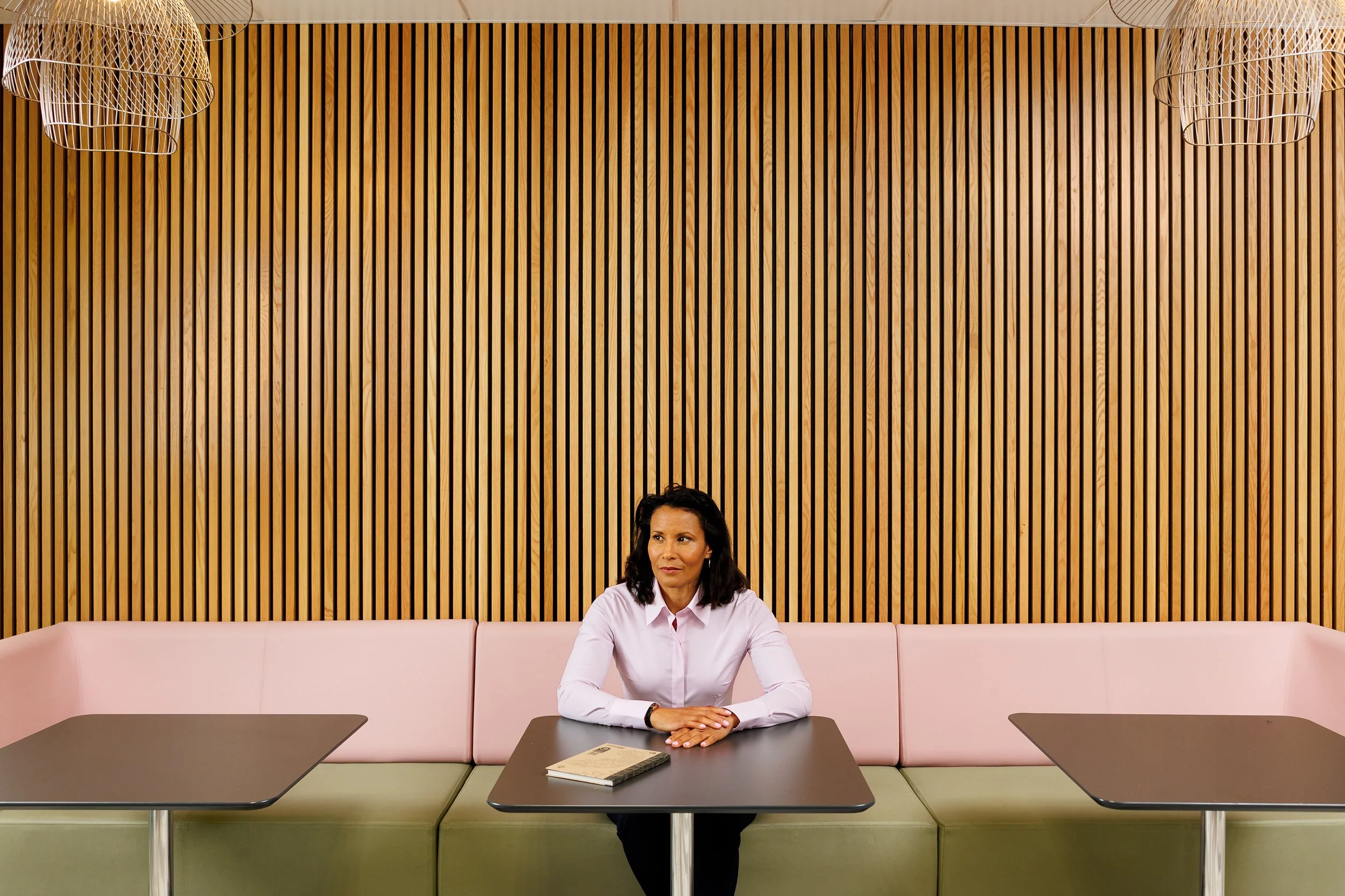 A businesswoman sits at a small table in a meeting space