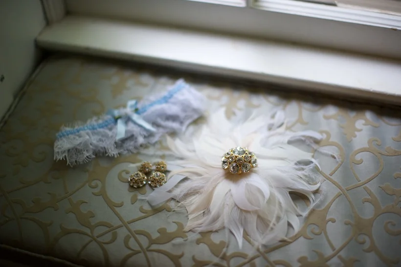  Wedding day detail photo by Elizabeth Glessner of Glessner Photography of Kate Spade earrings and broach from Rent the Runway and feather sash by Alice Hart Couture Millinery via Etsy at the backyard wedding of J.P. Perkins and Katherine Henry in As