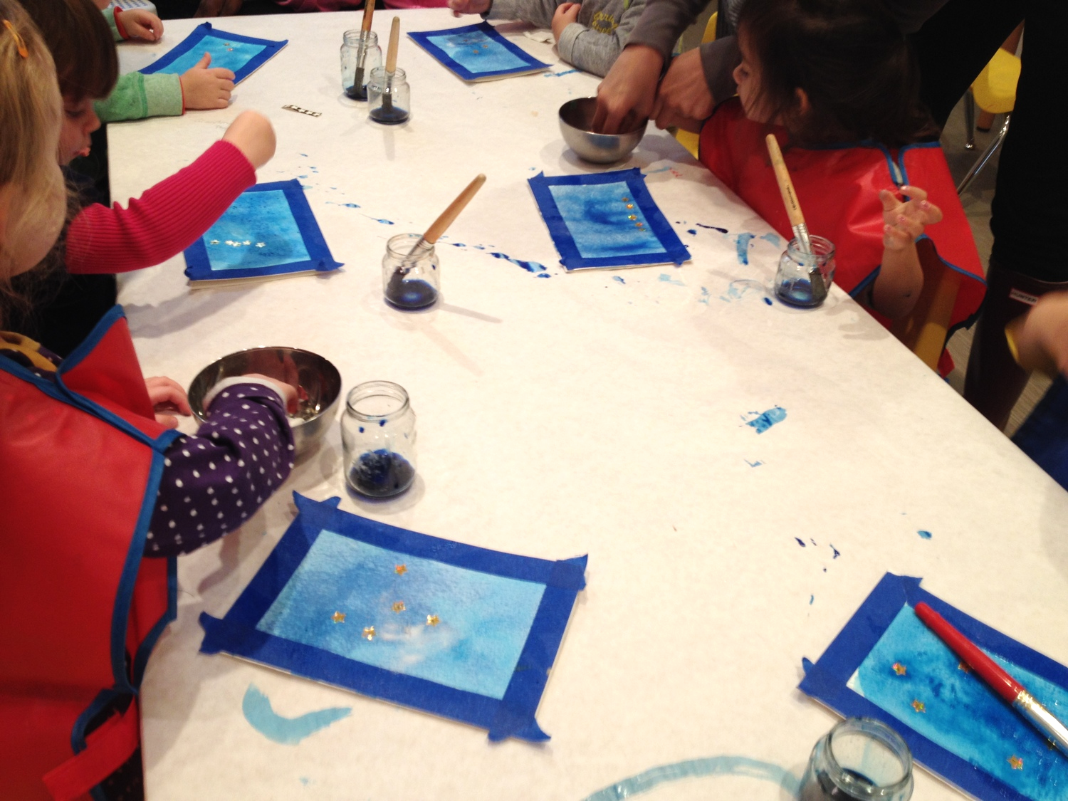 Toddler class creating watercolor star sticker resist paintings inspired by How to Catch a Star, Oliver Jeffers.