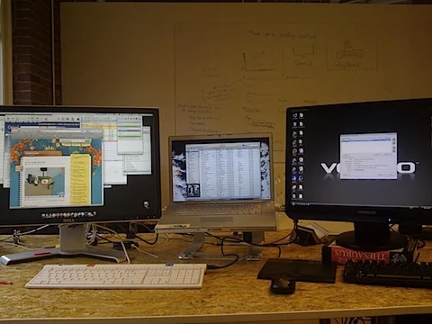 Macbook Pro in the middle driving the dell 24 inch on the left. Dell Vostro on the Right controlled with the mac keyboard and mouse using Synergy. Compulsory startup whiteboard in the background. Not shown in picture total mess of cables and bits of paper.