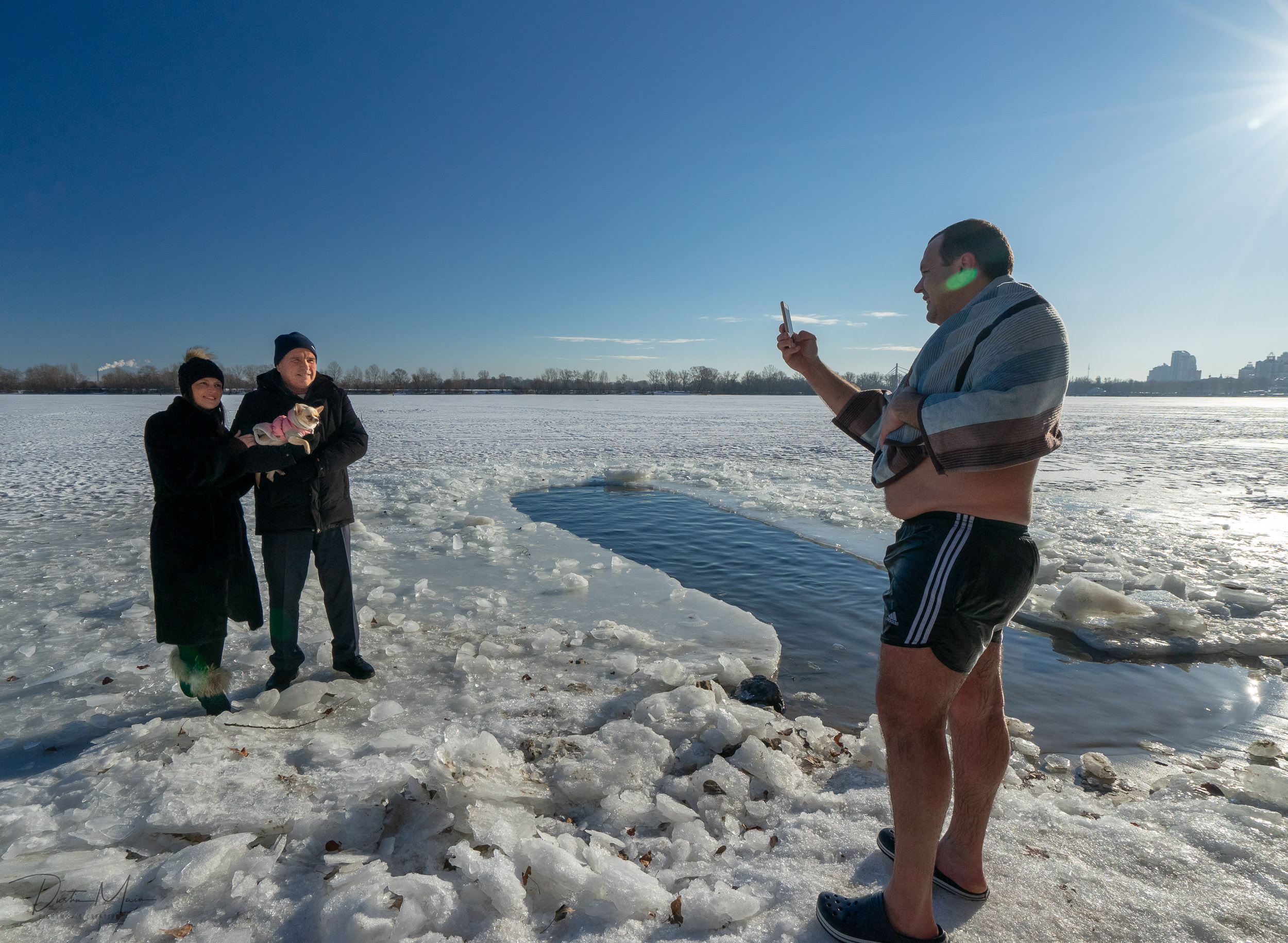  Half-naked swimmer comes out of the river and takes a photo for a couple who are holding their dog. © Dustin Main 2019 