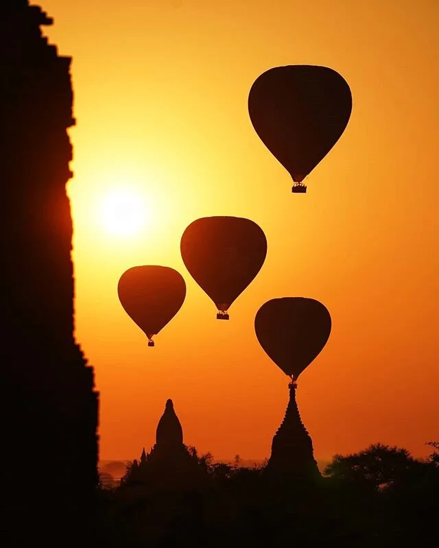 Balloons Over Bagan

It's an hour before sunrise in winter in Myanmar, and it's a little chilly, especially if you're on a motorbike.  If you're like my buddy @aungkomyint then you may need "double trousers" to keep the cool air at bay and prevent the shivers

Now at 45min before sunrise, the sky is changing rapidly.  From pitch black sky and a dash of stars, to a deep blue that steadily lightens.  We call this the "blue hour." Most people aren't here to witness it, and it is their loss.  We're closer to the equator here, so the changing light happens quite fast and you don't want to miss a second

Once the sun finally peeks over the horizon, the landscape is awash with light.  Moments later, the first hot air balloons begin to pop up

Bagan is famous for hot air ballooning.  Pilots line up from around the world to work a season here.  And who could blame them?  It's an exceptional way to view the Bagan plains and the more than 2000 monuments here.  The golden light that the country is known for certainly doesn't hurt

This morning, were on the ground, and the iconic balloons are slowly floating by.  Even down below, it's a pretty special sight

#UnTourToMyanmar #ThisMyanmarLife #Myanmar #burma #myanmarmagic #thediscoverer #passionpassport #hotairballooning #bagan #temple #asia #sillhouette