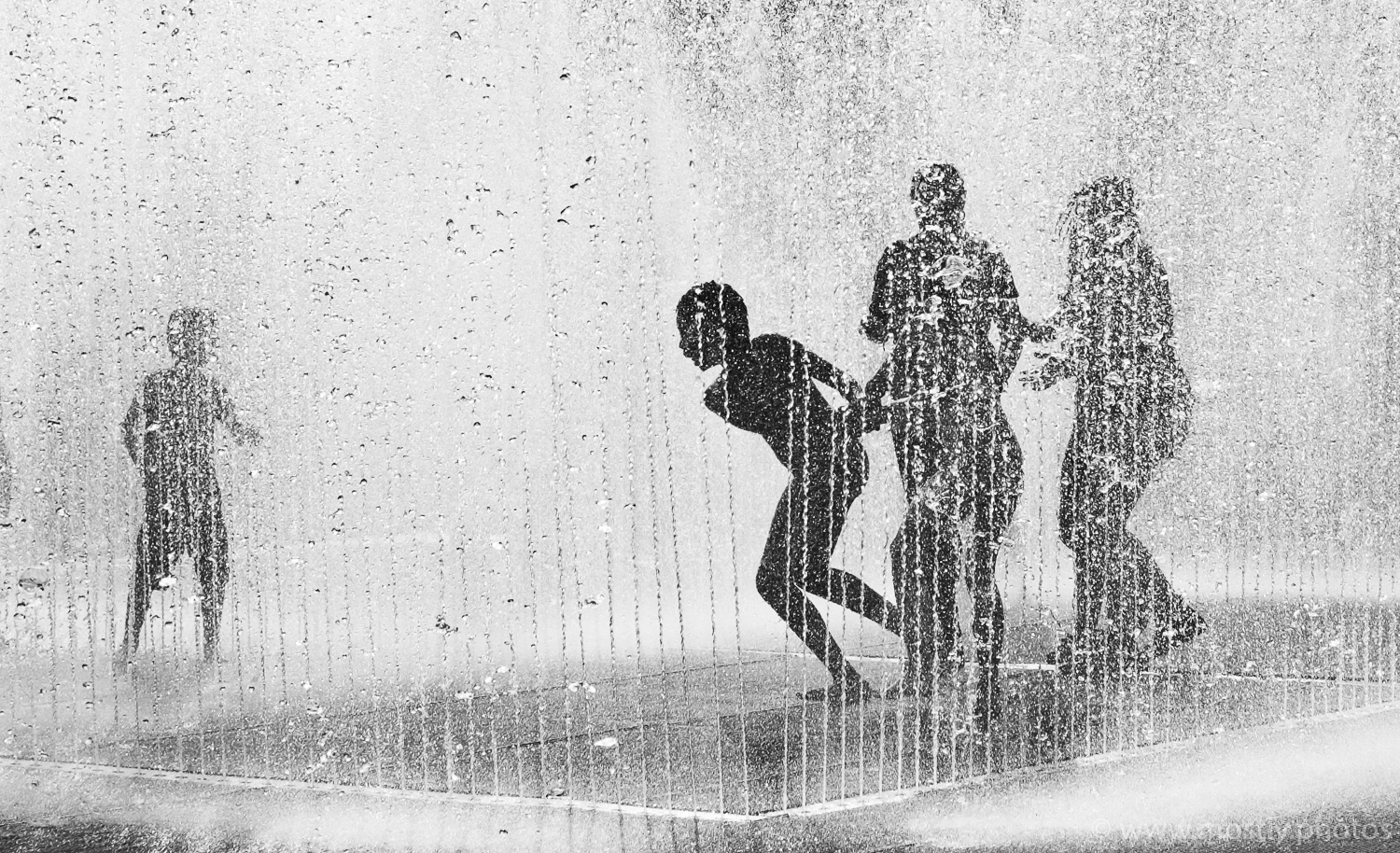 Silhouettes of people playing in the Fountains on Londons Southbank in the Summer.