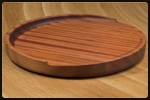 Idea #1: The Trencher Sapele Mahogany Round Wood Reversible Cutting Board. Beyond stunning and so very thoughtful! The details: The Grothouse Round Trencher Cutting Board -- 15” in diameter and 2” in height -- is a uniquely crafted working surface. The gradual sloped design collects juices in the well at the back of the board — and away from the work area — making it a popular choice for slicing anything from watermelon to carving meat. The trencher reverses to a flat surface, perfect for general chopping and prepping tasks or slicing bread or serving hors d'oeuvres. Shown here in Sapele Mahogany, in red and brown tones with iridescent stripes, this item is just $345 with free shipping! (Other woods are available; optional laser engraving at an additional cost.) 