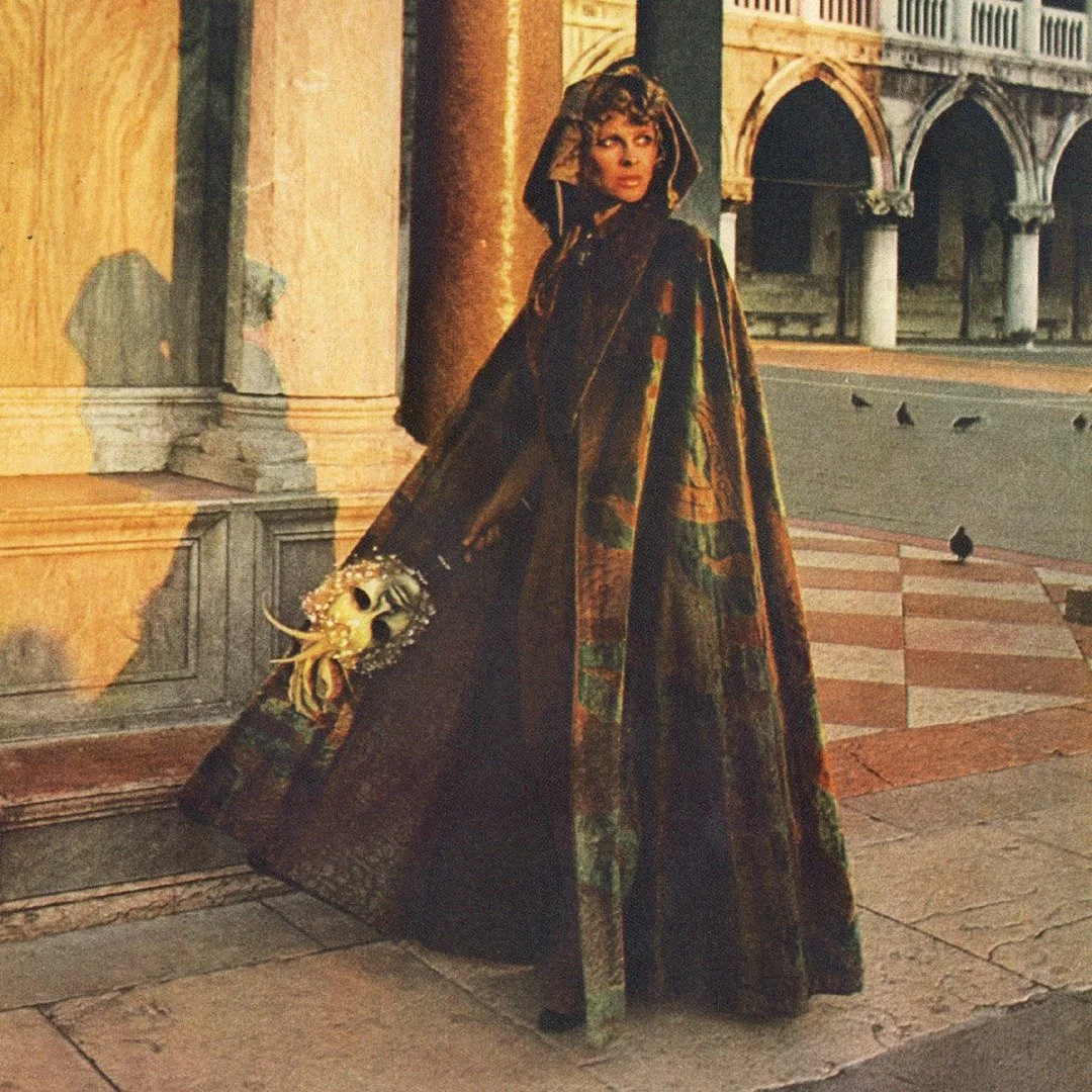 Julie Christie, captured by Alfa Castaldi for Vogue 1973, brings the essence of Venice&rsquo;s Carnival to life. Dressed in a Fortuny &lsquo;Delphos&rsquo; cloak, the fabric&mdash;rich with intricate silver and gold prints&mdash;blends artistry with 