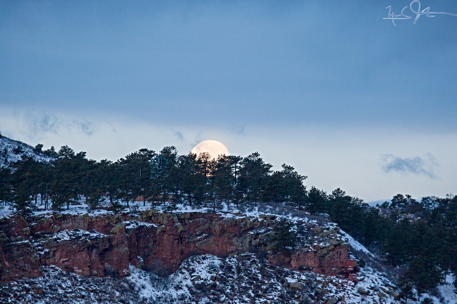 The moon drops behind the mountain just before sunrise.
