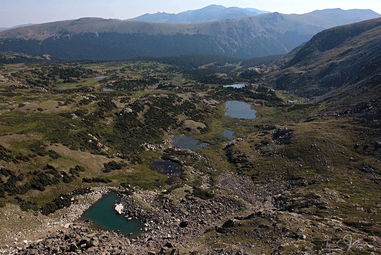 Looking from the Continental Divide over a few unnamed lakes towards Forest Canyon, with Trail Ridge and Trail Ridge Road in the distance.
