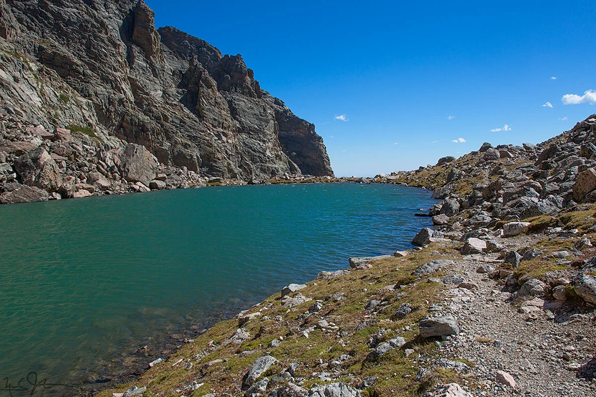 Andrews Tarn lies at around 11,500 feet elevation, just below Andrews Glacier, just east of the Continental Divide in Rocky Mountain National Park. This photo looks eastward away from the Divide and the glacier, towards the steep drop-off into the canyon below.