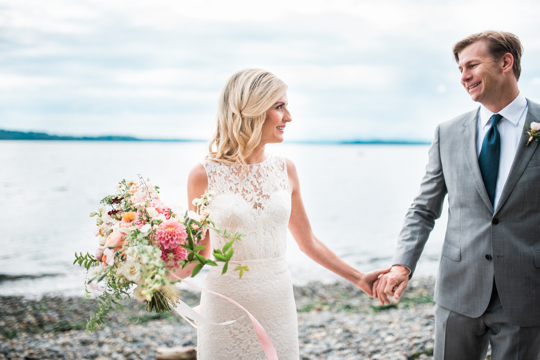 182-wedding-couple-walking-on-driftwood-holding-flowers-by-floret-floral.jpg