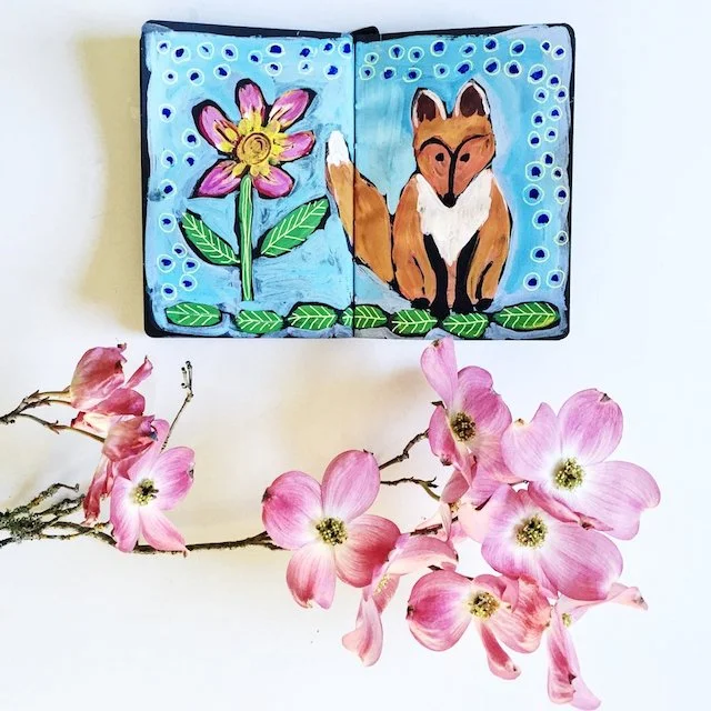 sketchbook painting of a fox and flower against blue background
