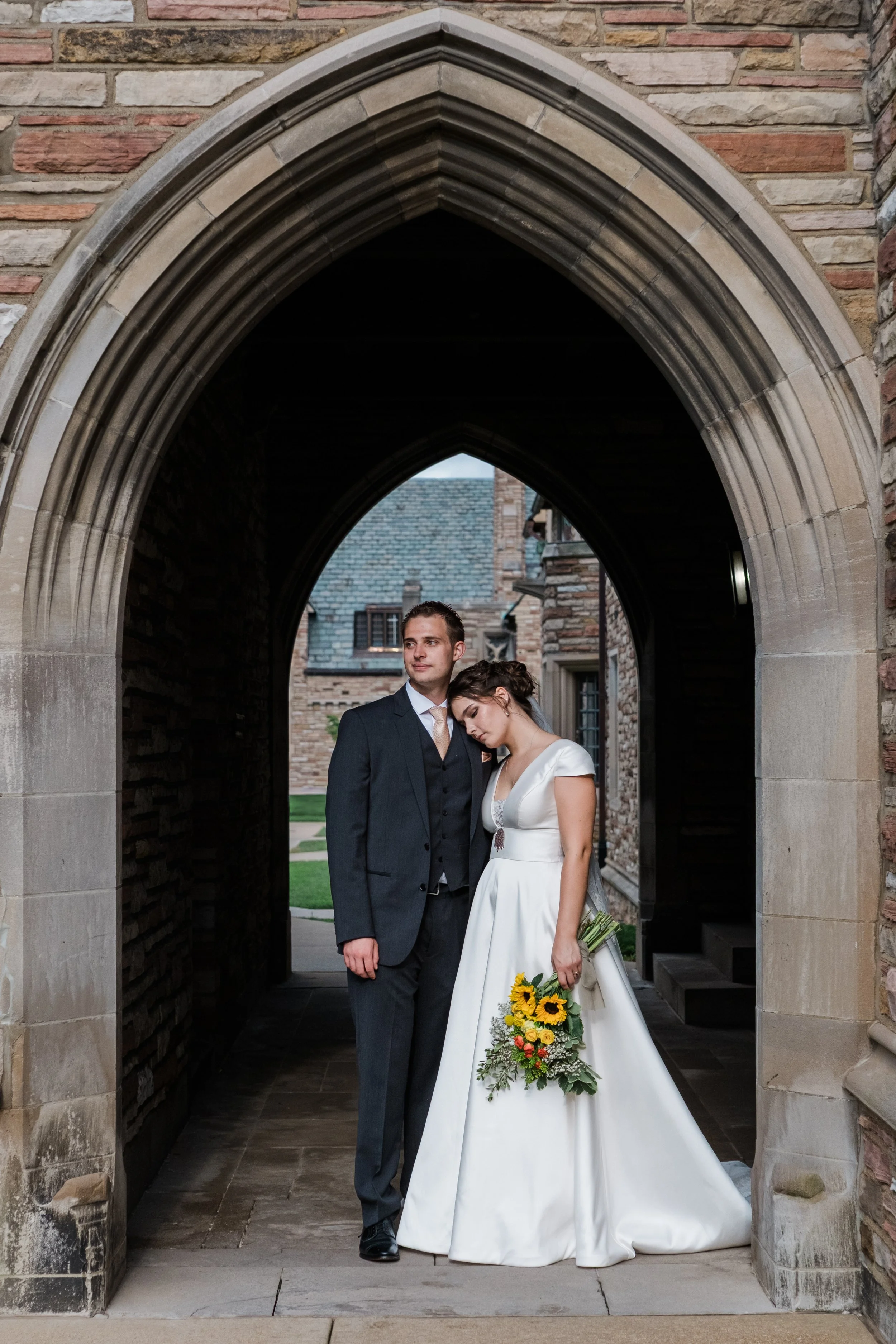 A groom and bride wedding portrait under a curved entrance at the campus of Concordia Seminary St. Louis during their wedding in Missouri.