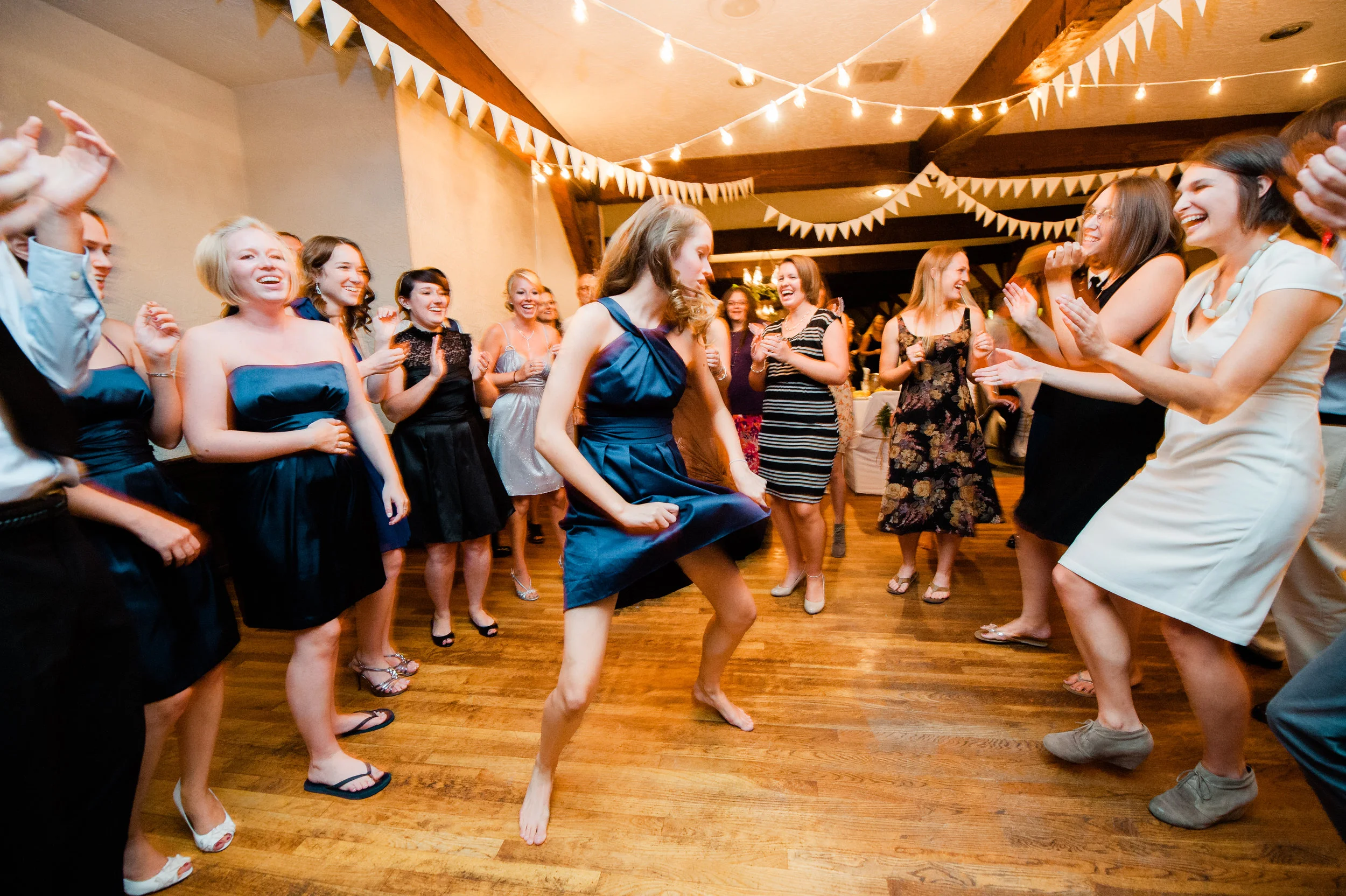 Group of women dancing and laughing at a celebration or party in a decorated indoor space.