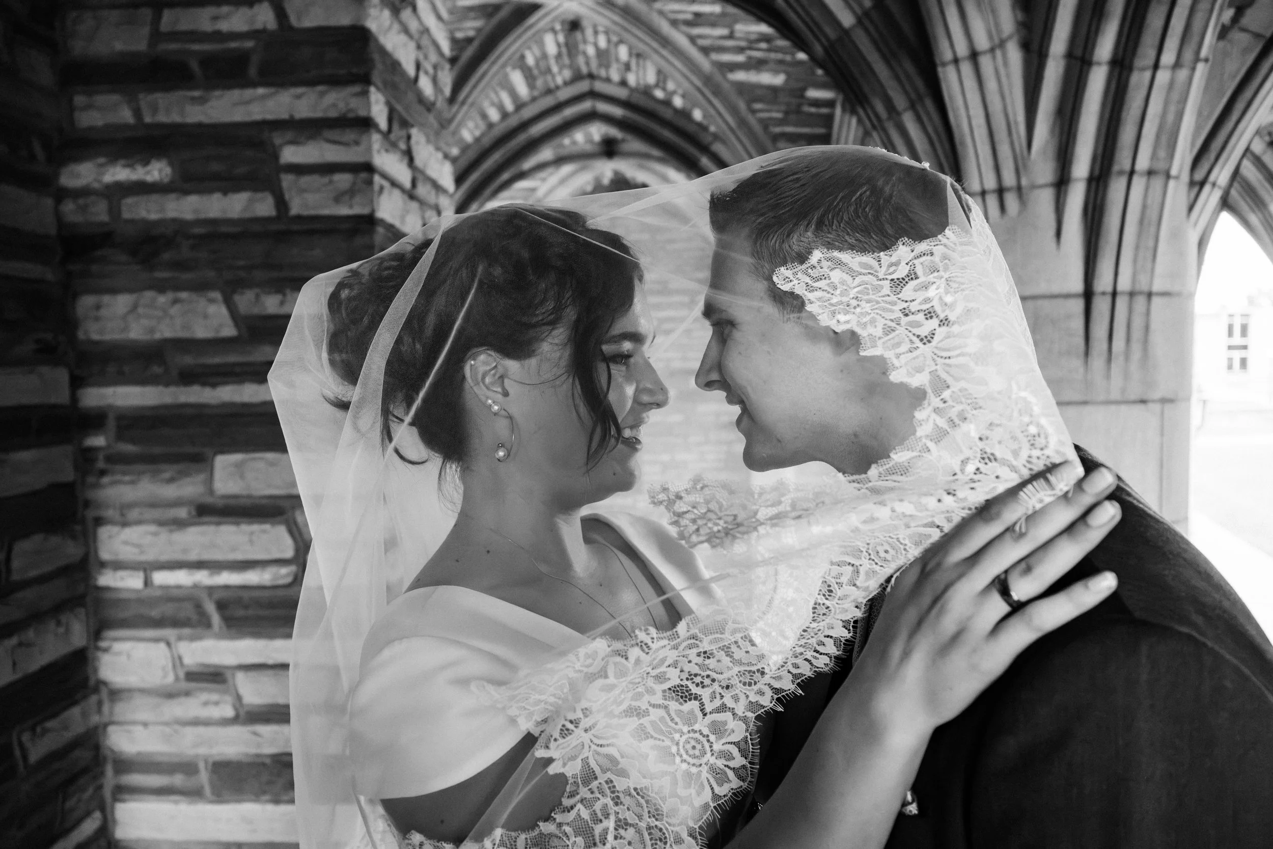 A groom and bride under a veil in a wedding portrait at the campus of Concordia Seminary St. Louis during their wedding in Missouri.