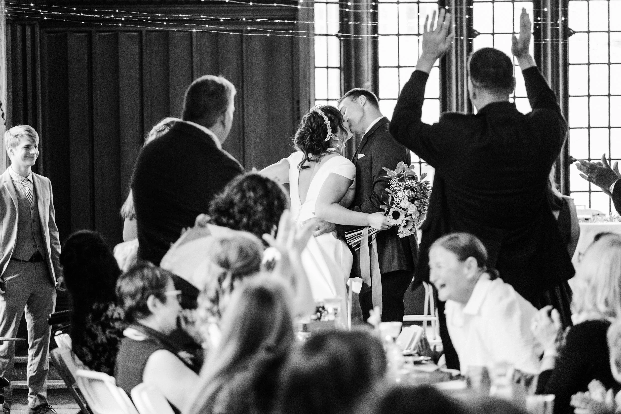 People celebrate and cheer as a bride and groom kiss after entering their reception during their St. Louis wedding.