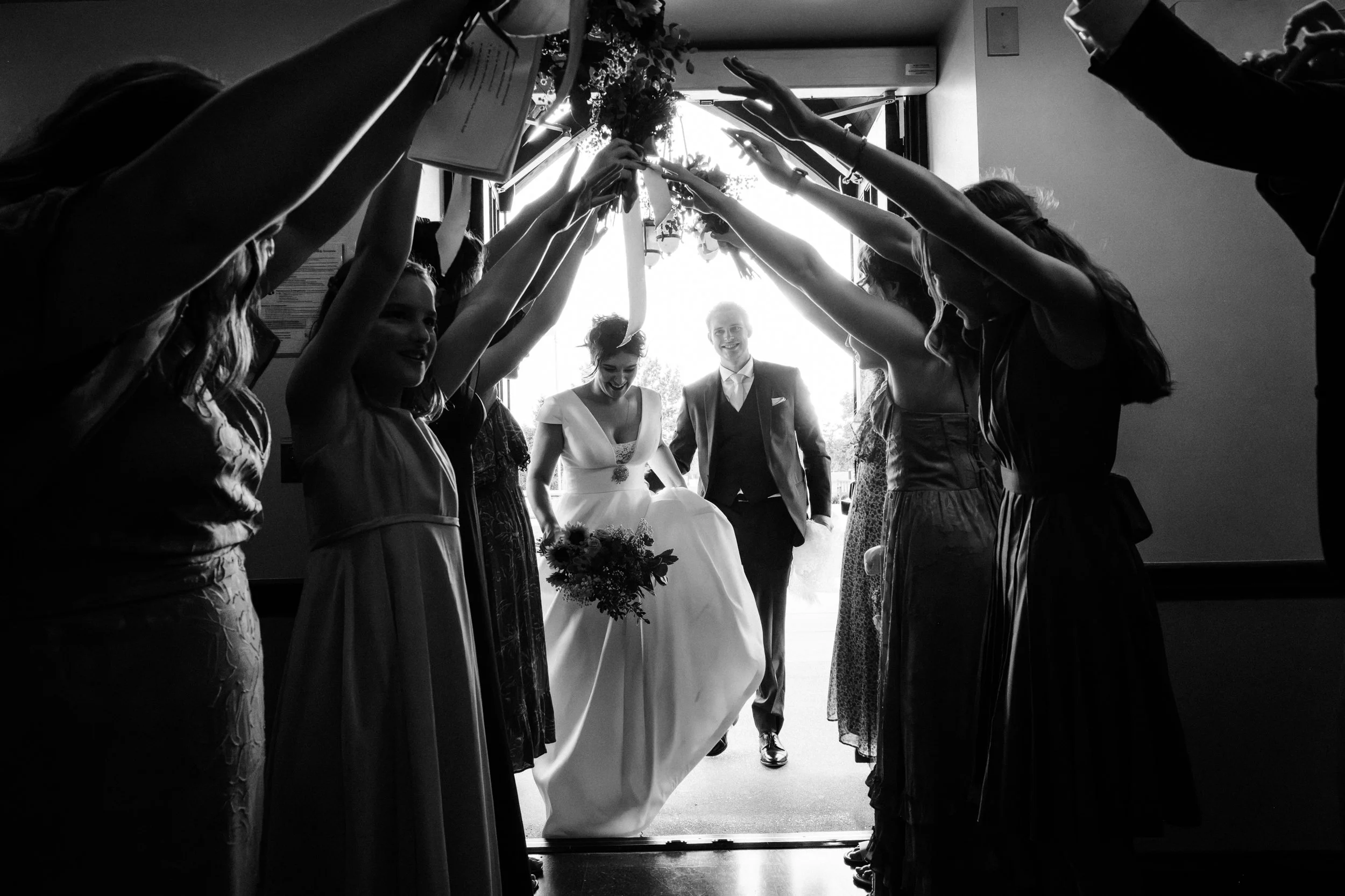 A bride and groom make their way into their reception as the bridal party make a tunnel with their arms at St. Louis, Missouri wedding.