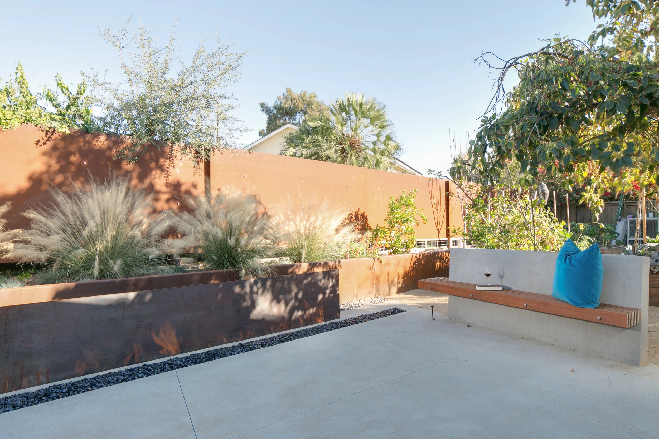 The concrete and wood bench is perfect for relaxing at the fire pit with Cor-ten backdrop