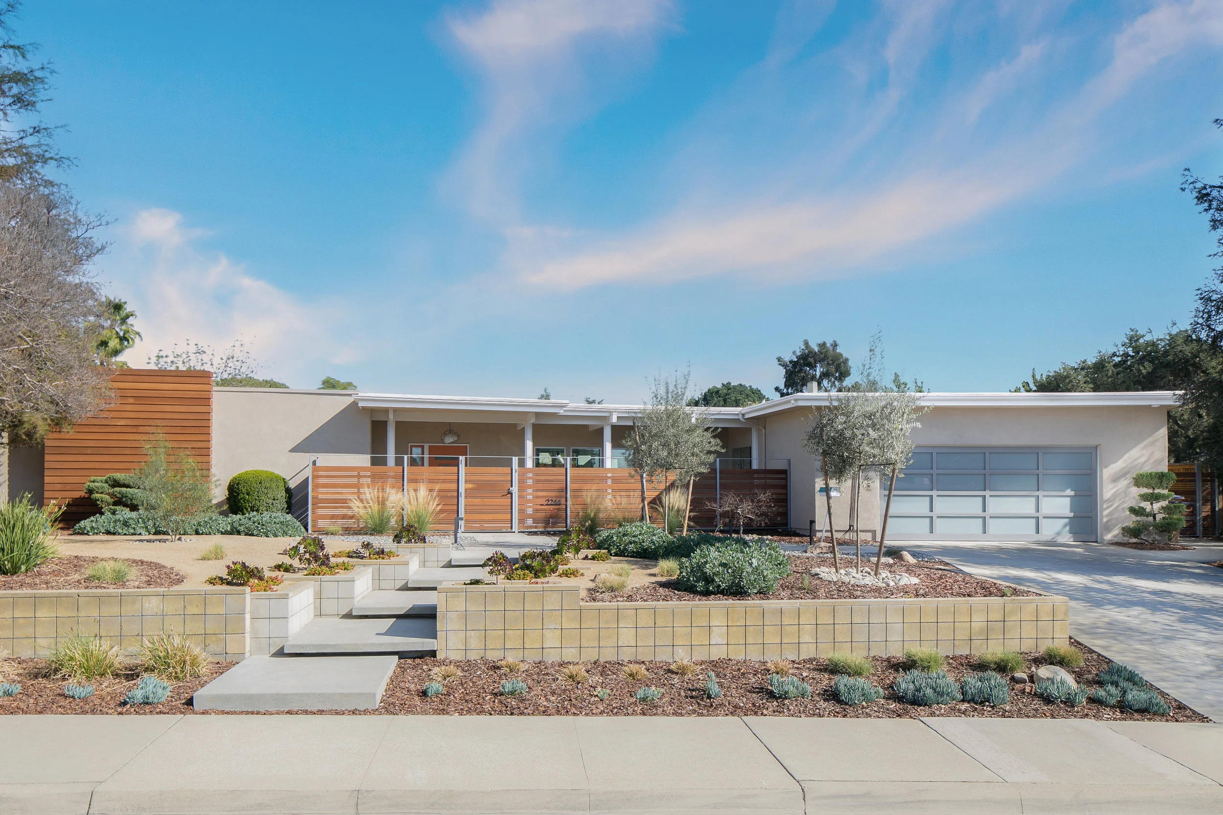 The new fence, wood accents, landscaping and steps leading to the entry continue the timeless mid-century design of this home