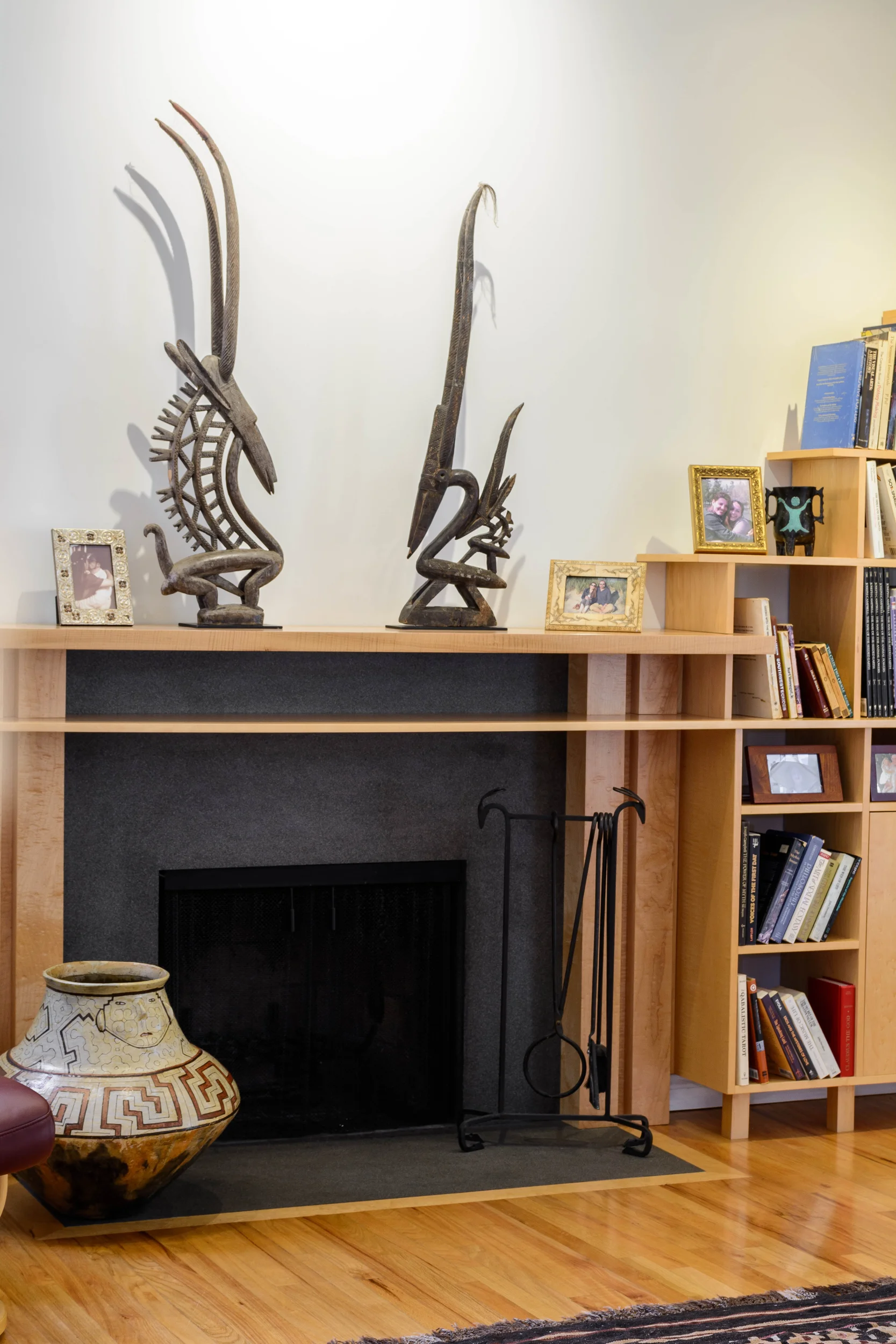 Living room fireplace with absolute black granite and a curved maple mantel which seamlessly transitions with the bookshelves