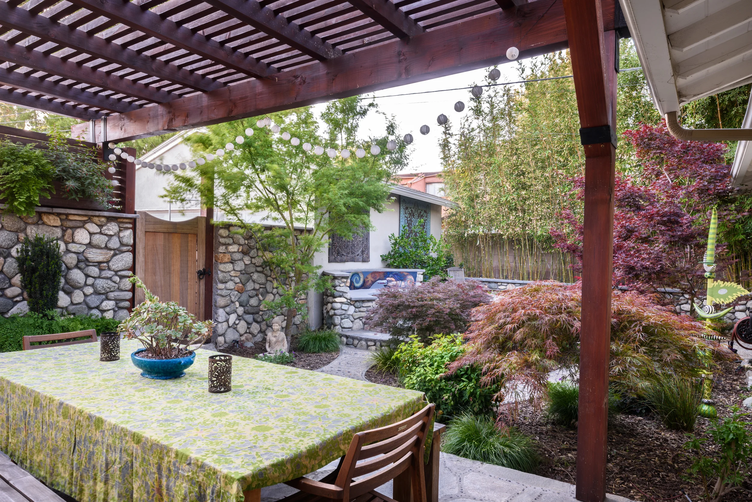 Wood pergola hand-rubbed oil finished providing for an outdoor dining area giving onto a serene Asian-inspired woodland backyard