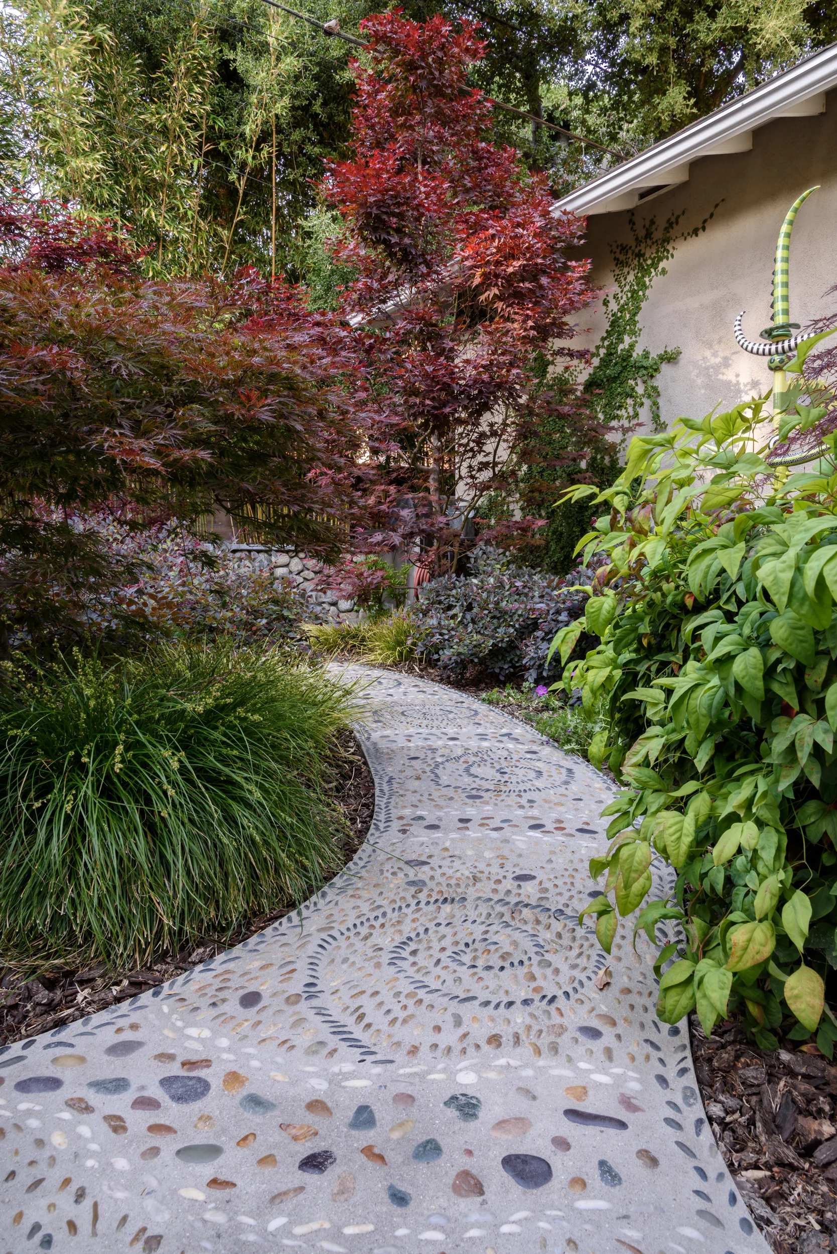Asian-inspired woodland backyard with bamboo, Japanese maple and mosaic pebble pathways for a peaceful retreat