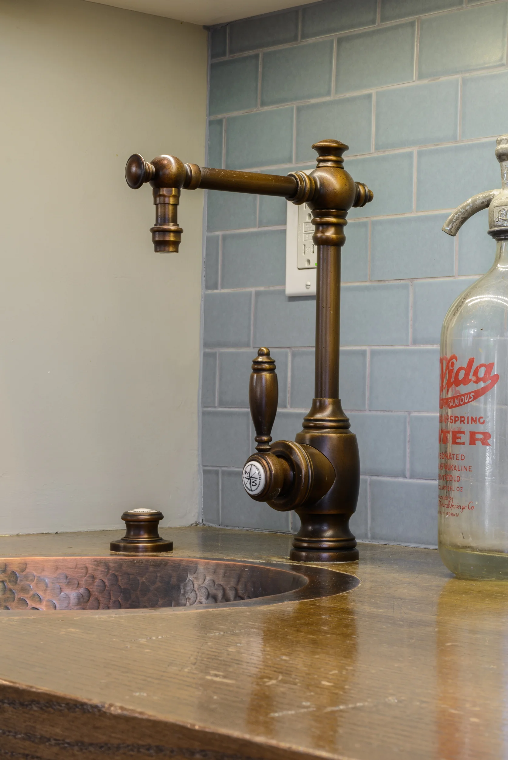 Copper bar sink on a wood counter with glass tile backsplash