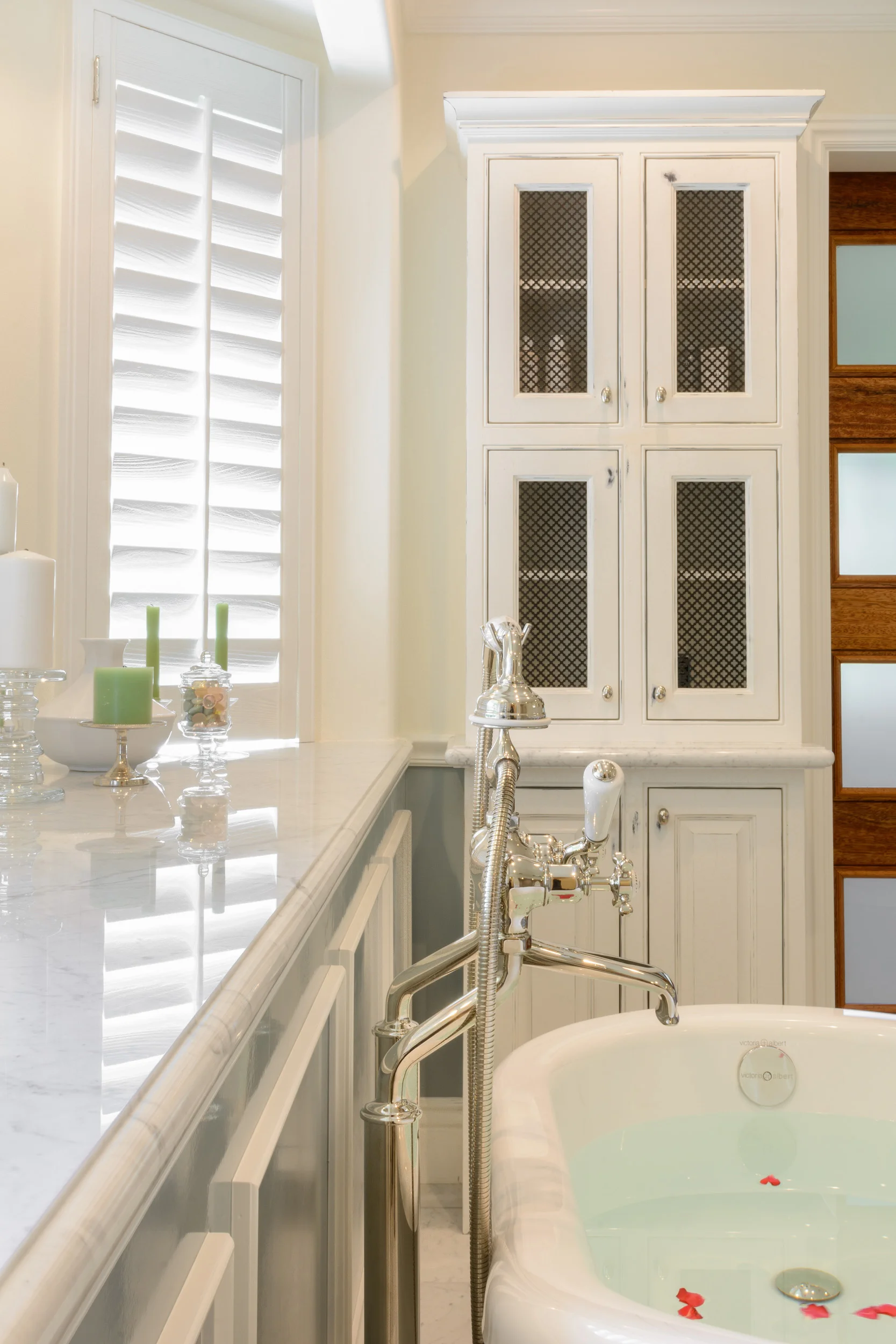 Marble slab bay window counter, traditional polished nickel tub filler and distressed white bathroom cabinets